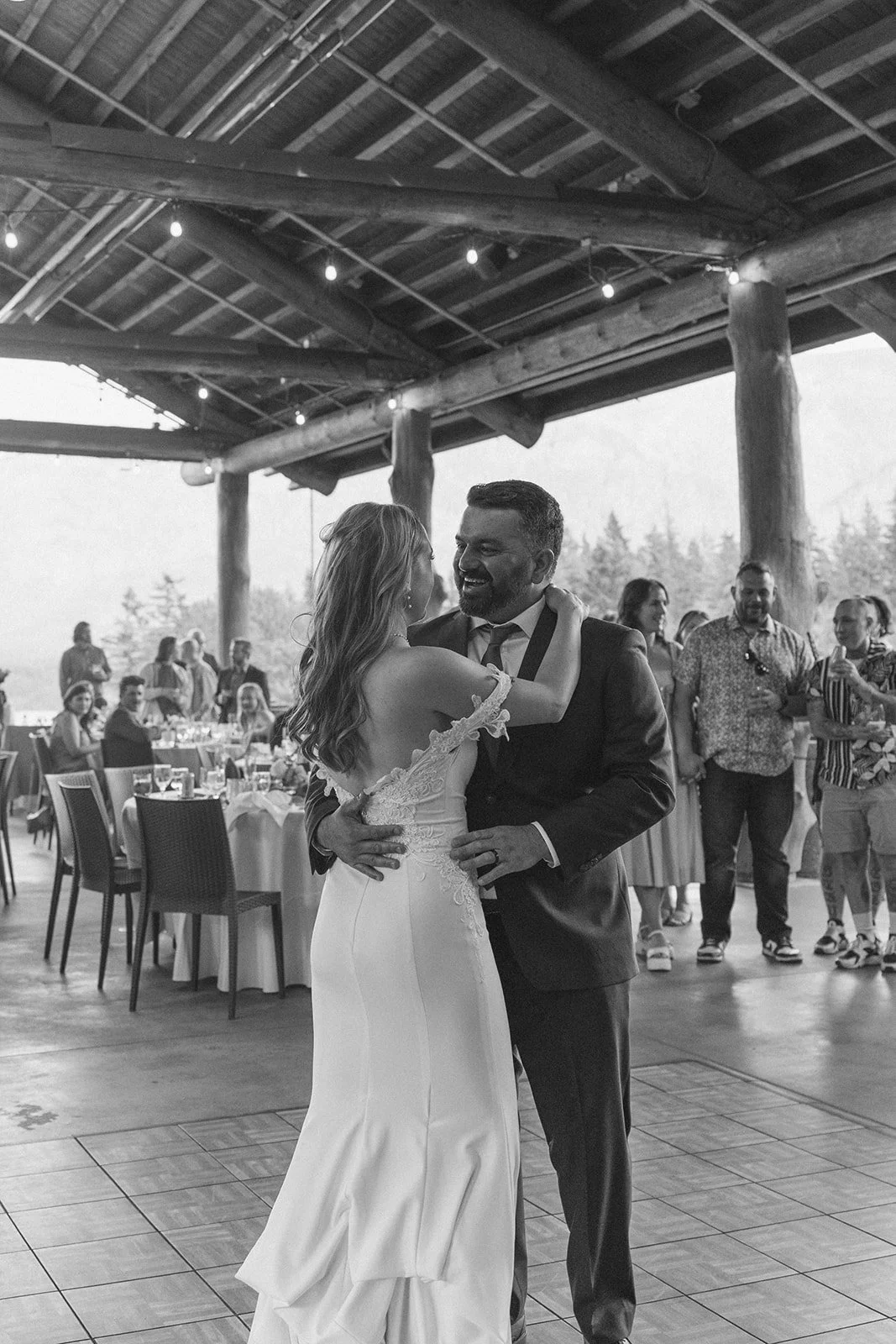 Dancing under heavy timber beams and cafe lights with guests watching