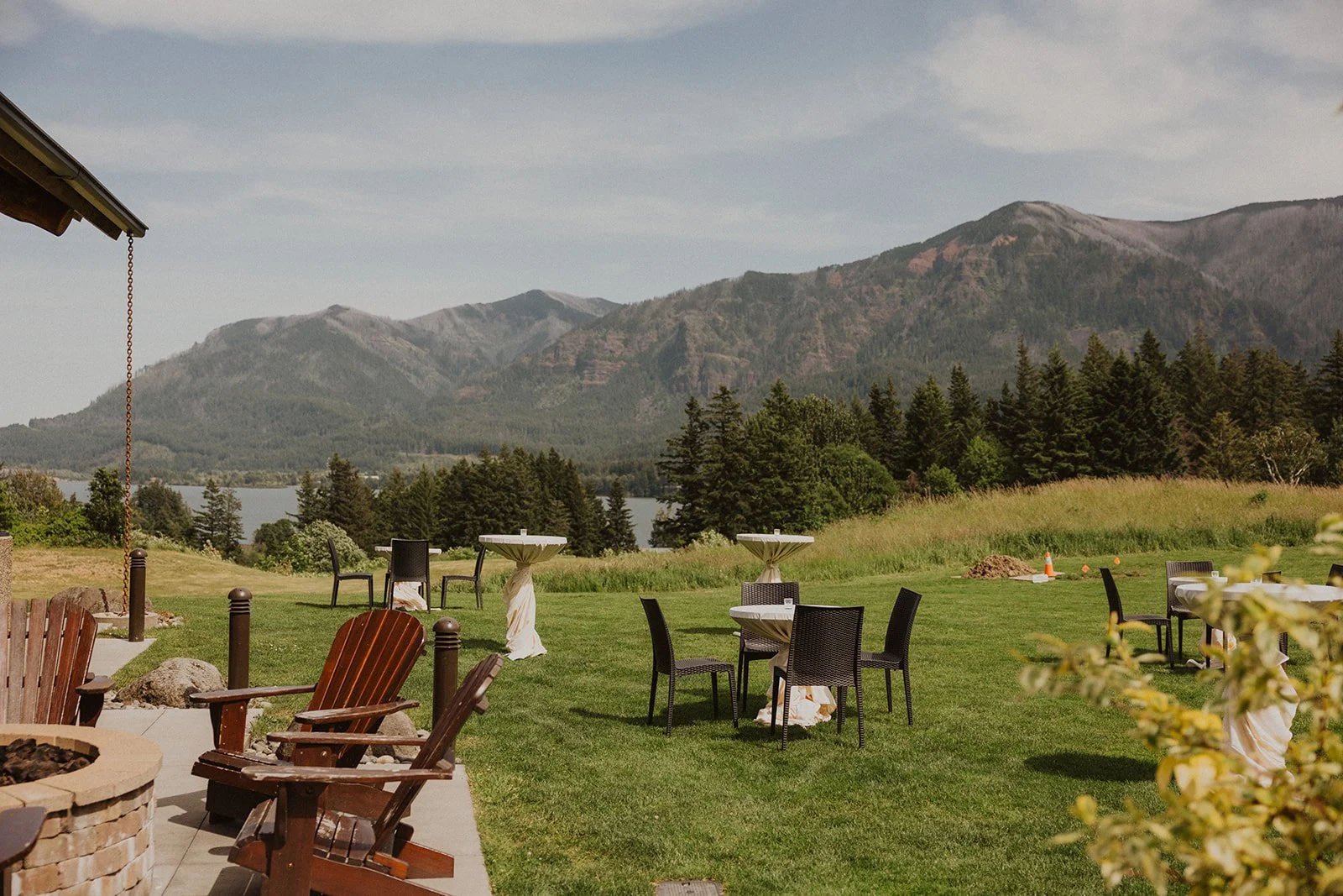Cocktail tables and low wooden chairs set out on grass before sunset