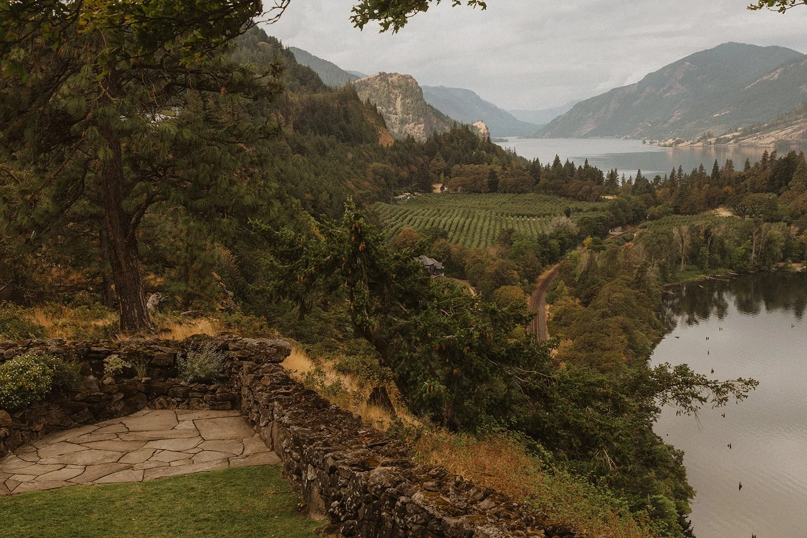 Gorge seen from a stone terrace with orchards and water below