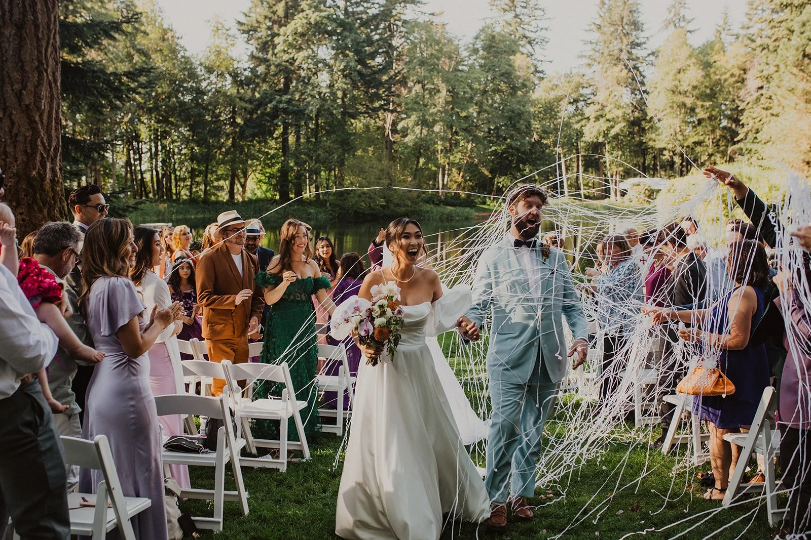 Newly married couple walking back down the aisle together after their Bridal Veil Lakes wedding ceremony while guests celebrate.