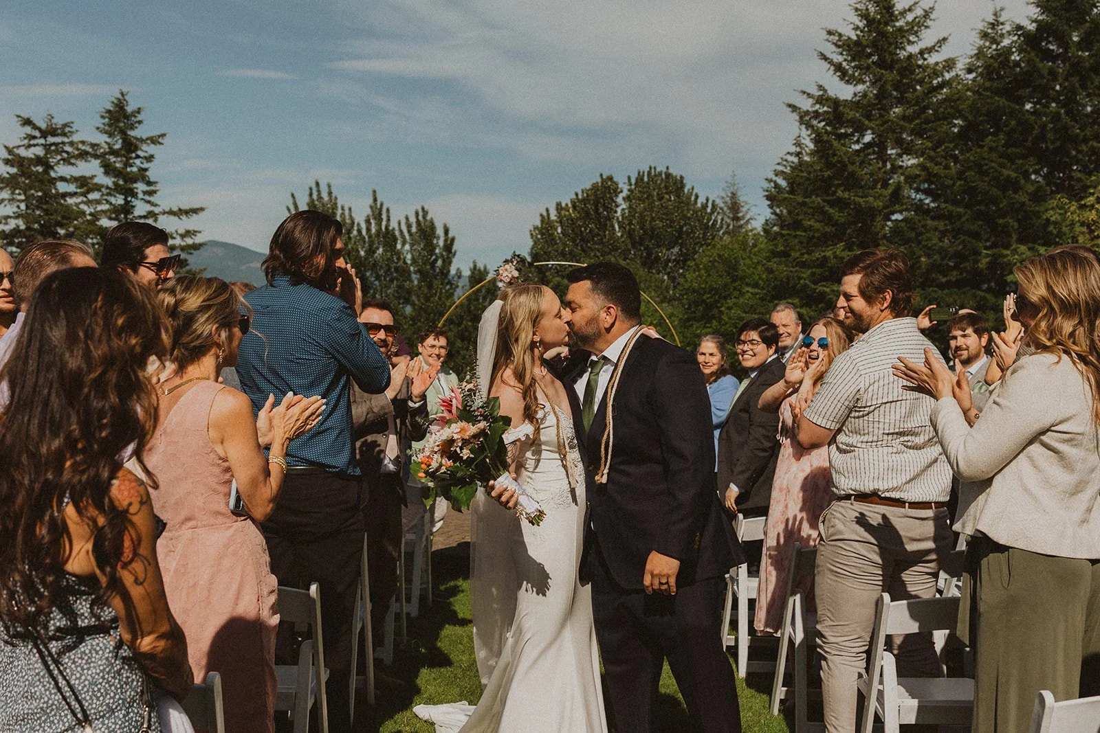 Couple sharing their first kiss after the ceremony while guests applaud at Skamania Lodge.