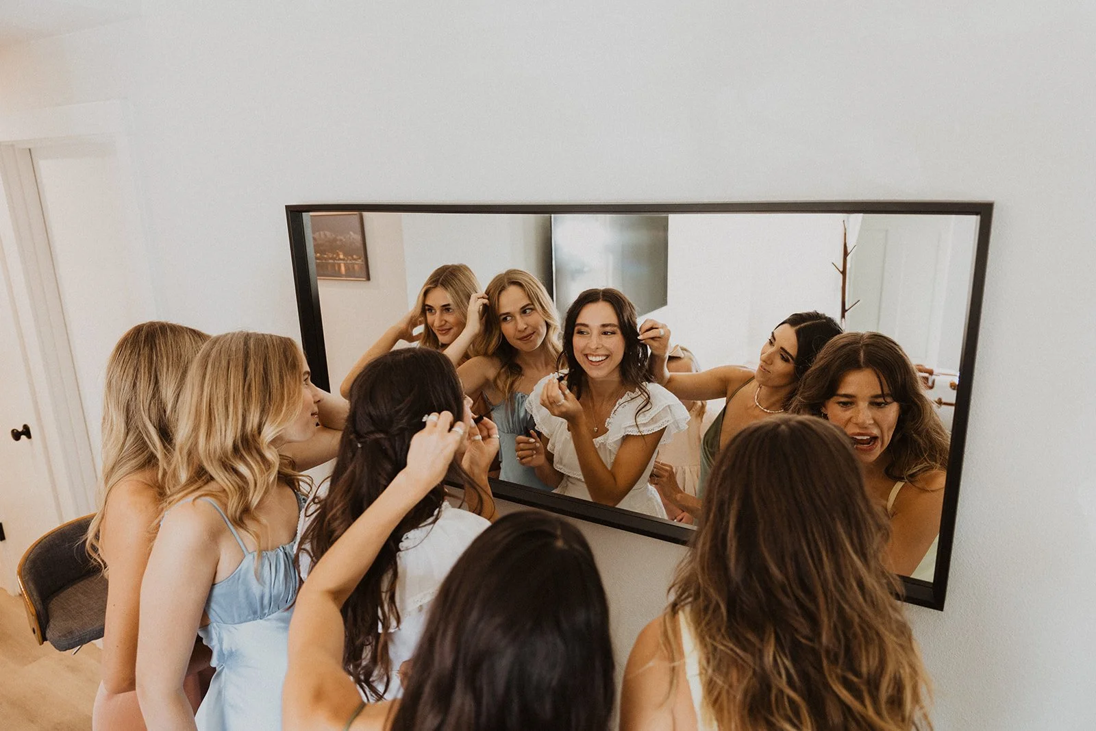 Bridesmaids getting ready together in mirror with bride during wedding morning