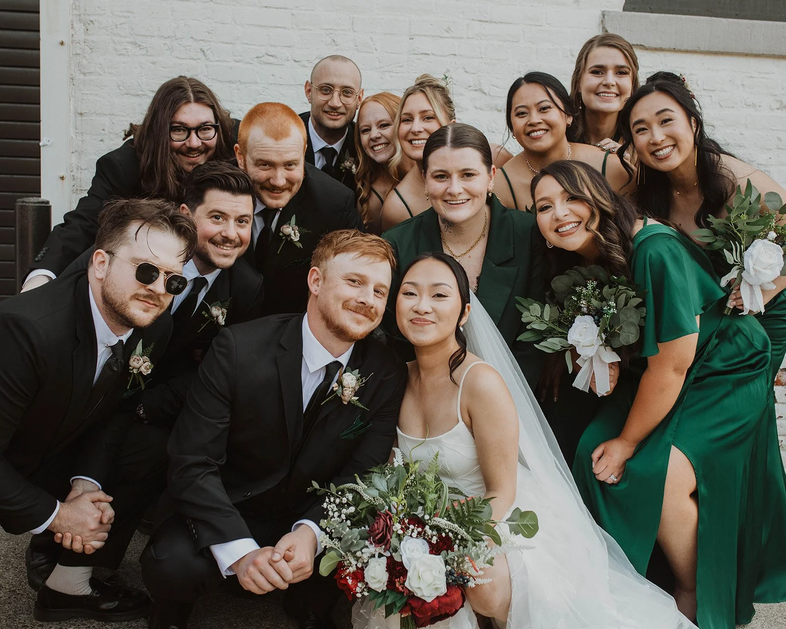 Bride, groom, and wedding party gathered together for a group portrait outside The Castaway wedding venue in Portland.