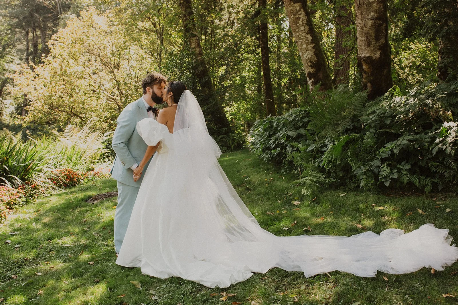 Romantic first look of the bride and groom embracing beneath the bride's veil during wedding portraits at Bridal Veil Lakes in Oregon.