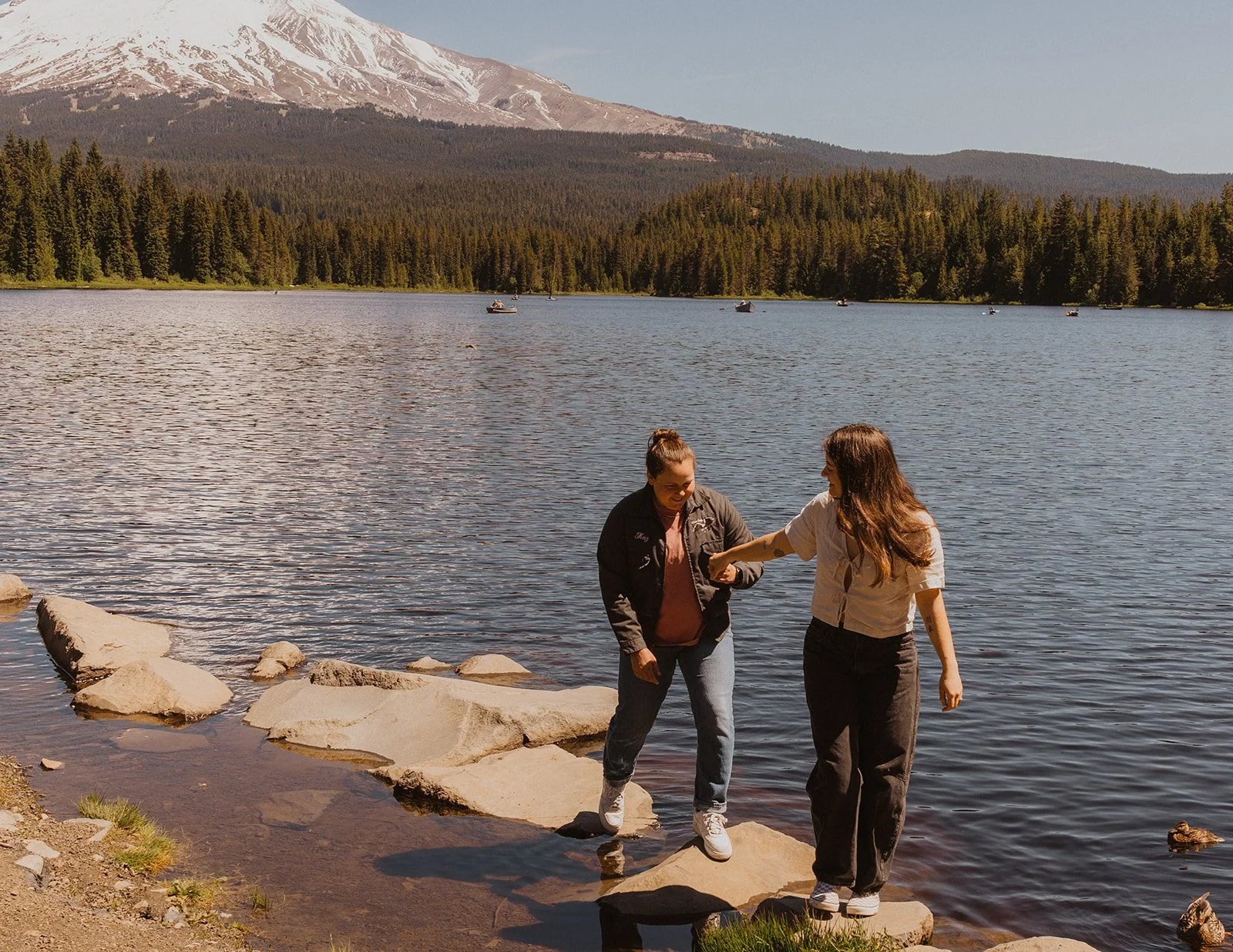 Hand in hand across the stones with a duck paddling past at Trillium Lake
