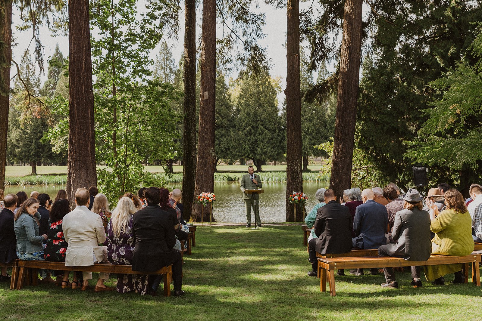 Grandparents sit together in the front bench row at a garden wedding ceremony