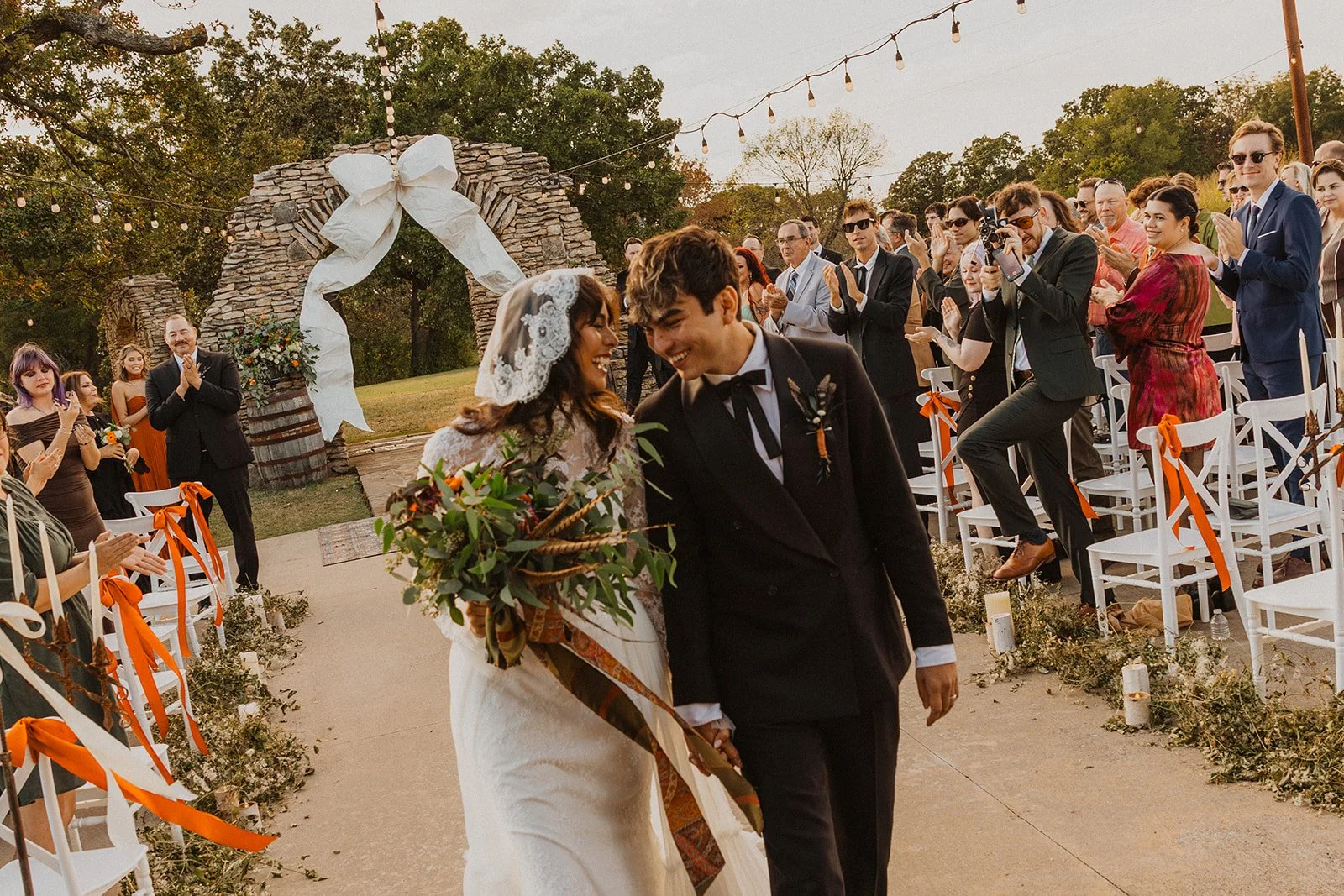 Newlyweds smiling and walking back down the aisle as guests applaud after their fall wedding ceremony at Bright Morning Farm.