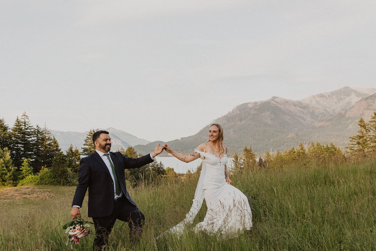 Bride leading her groom through a wildflower meadow during wedding portraits at Skamania Lodge.