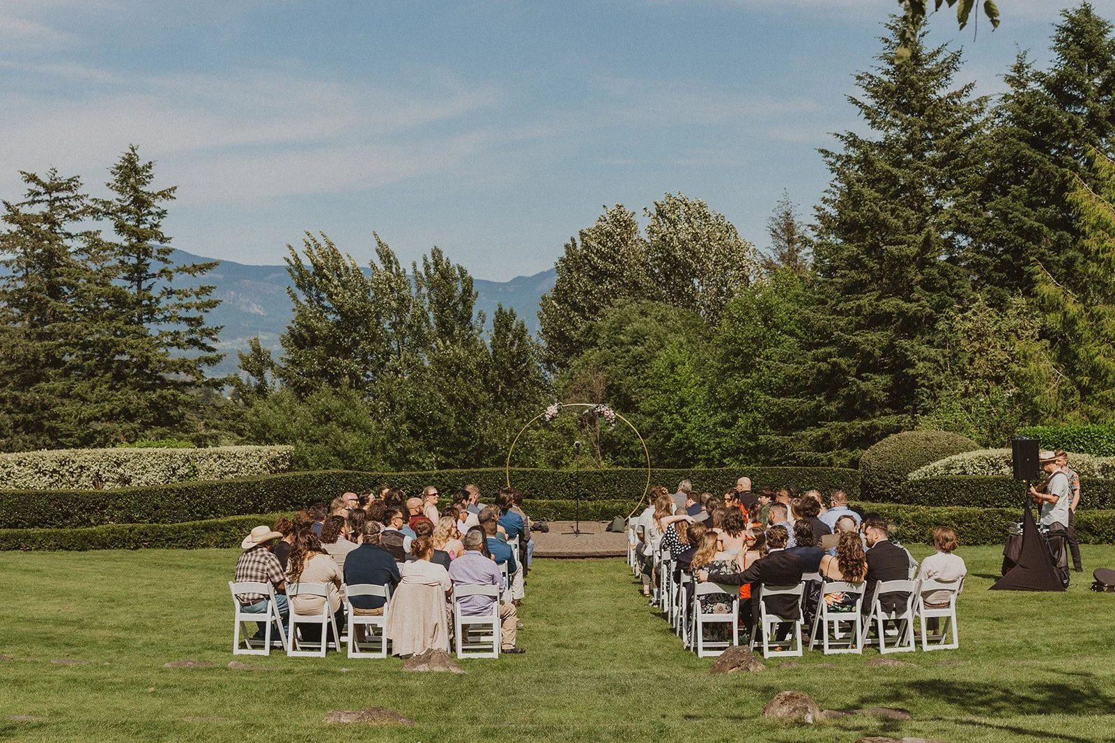 Guests seated for an outdoor ceremony with the Gorge visible past the arch