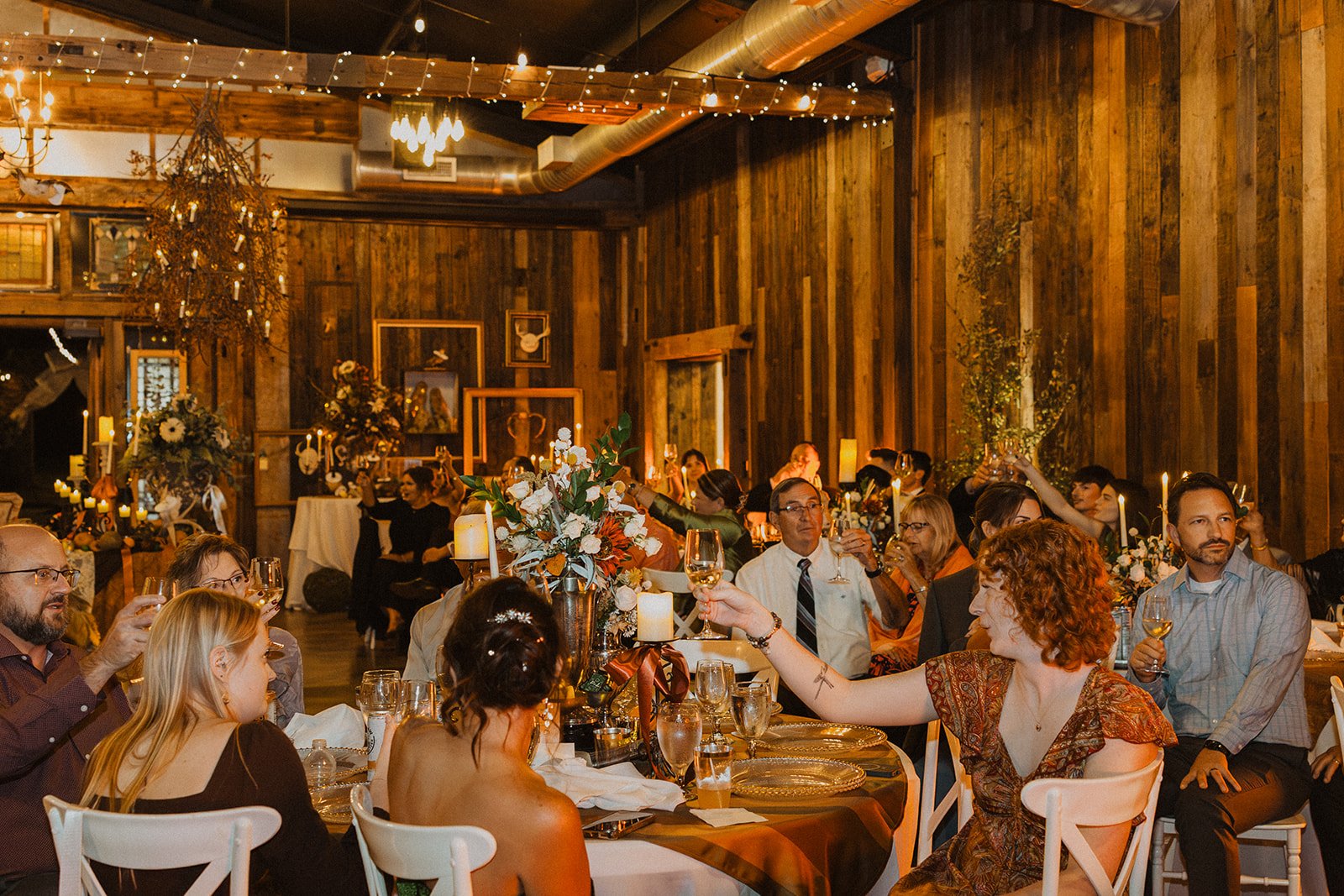 Wedding guests raising their glasses for a toast inside the rustic reception hall at Bright Morning Farm.