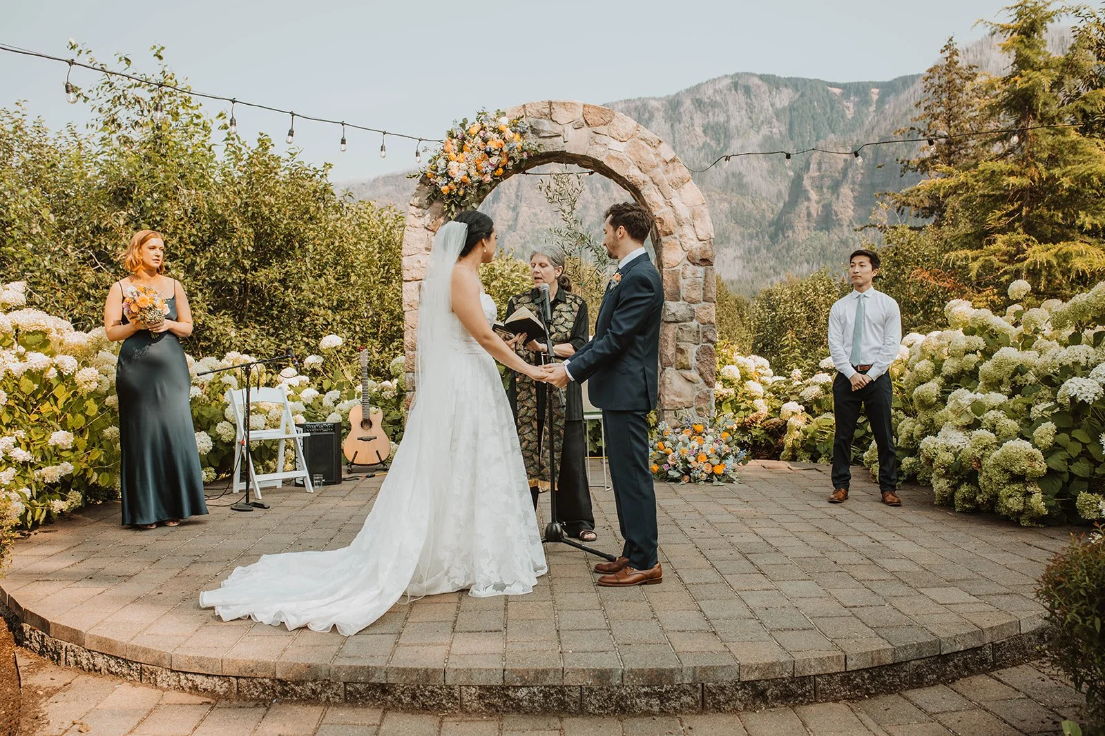 Vows exchanged beneath a stone arch framing the mountains across the river