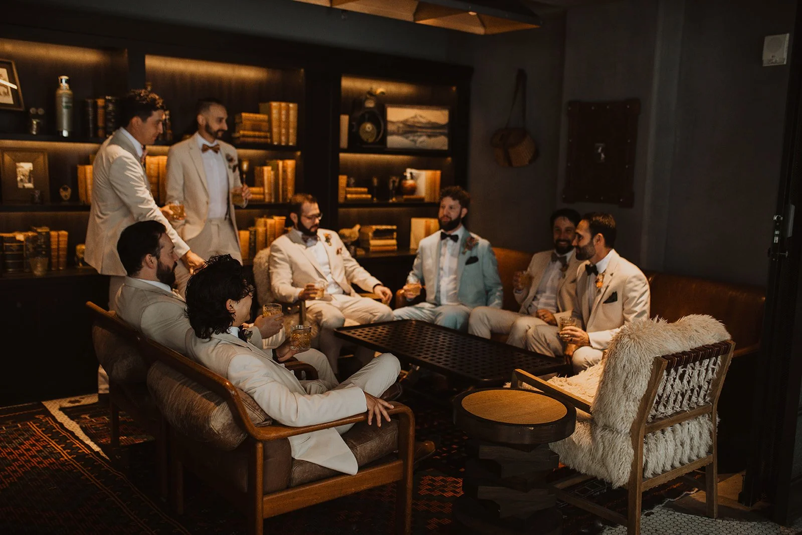 Groom and groomsmen relaxing together with drinks in the lounge while getting ready for a Bridal Veil Lakes wedding in Oregon.