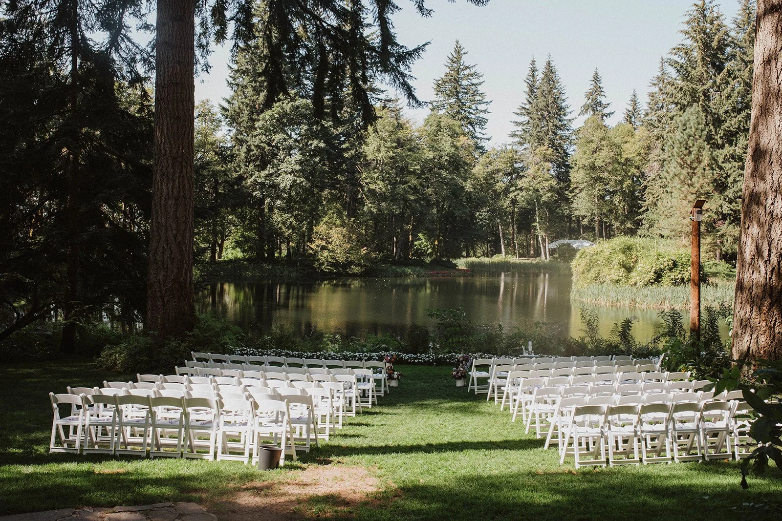 Rows of white chairs set facing a still lake ringed by firs