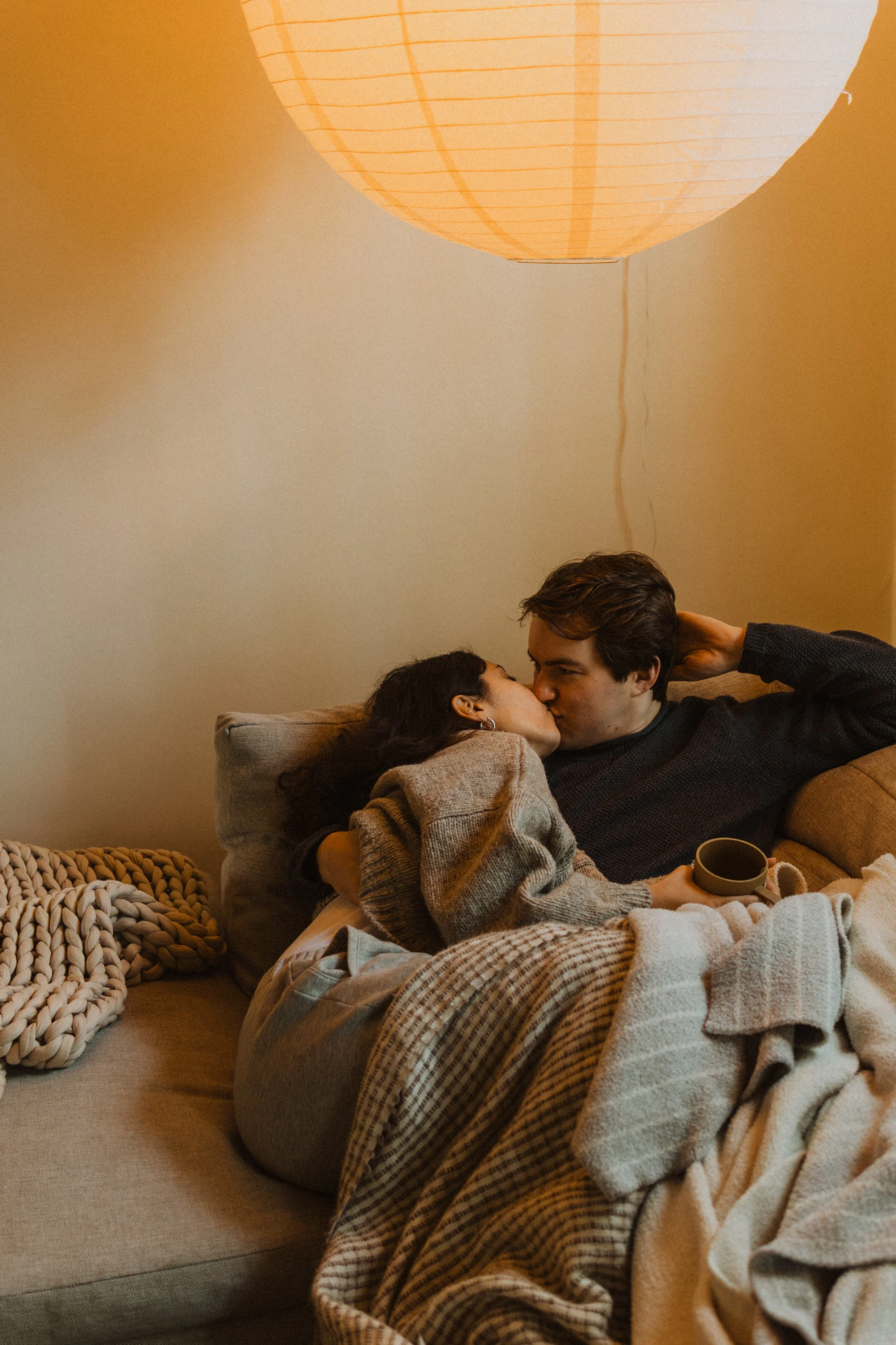 Couple getting cozy on their couch on a bright Sunday morning