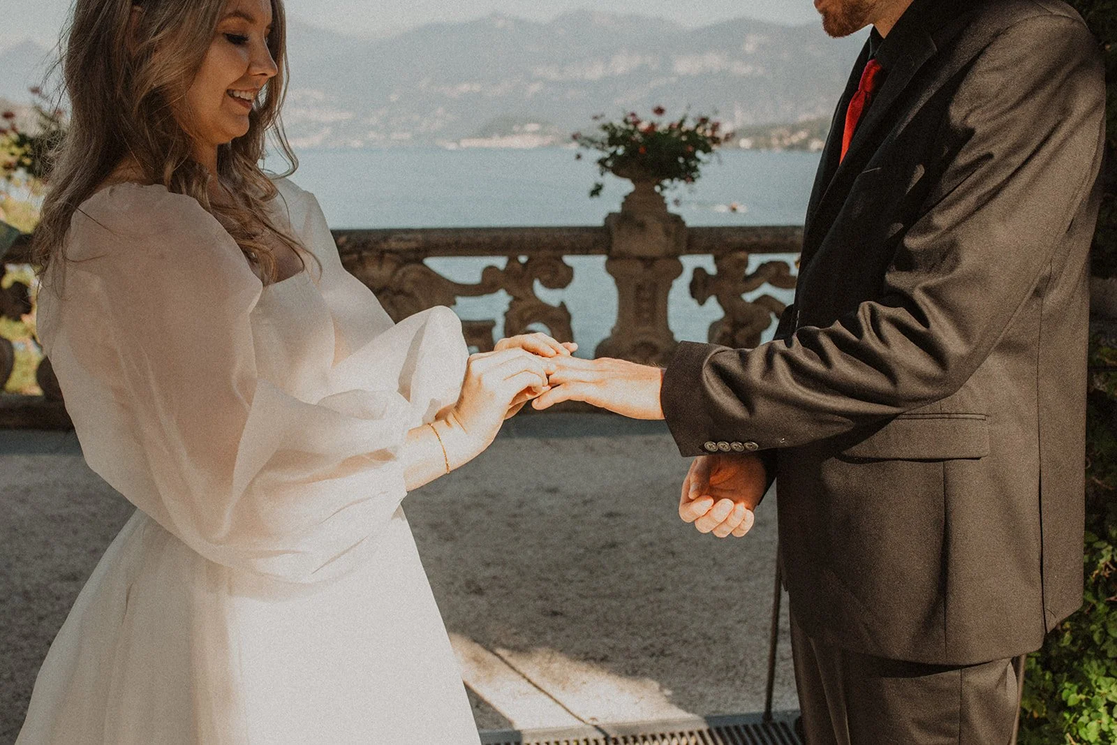 Bride placing a wedding ring on the groom's finger during their intimate ceremony overlooking Lake Como.