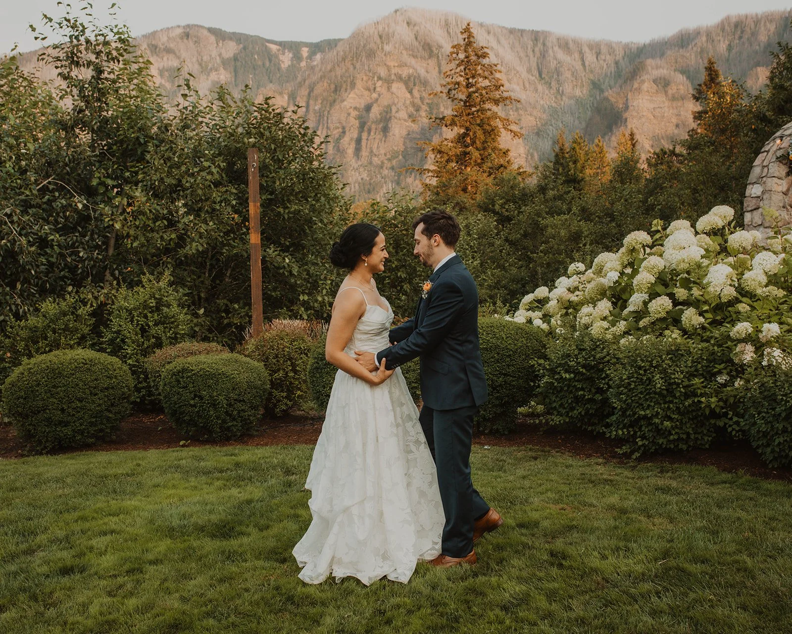 Standing together among tall hydrangeas with the river valley behind them