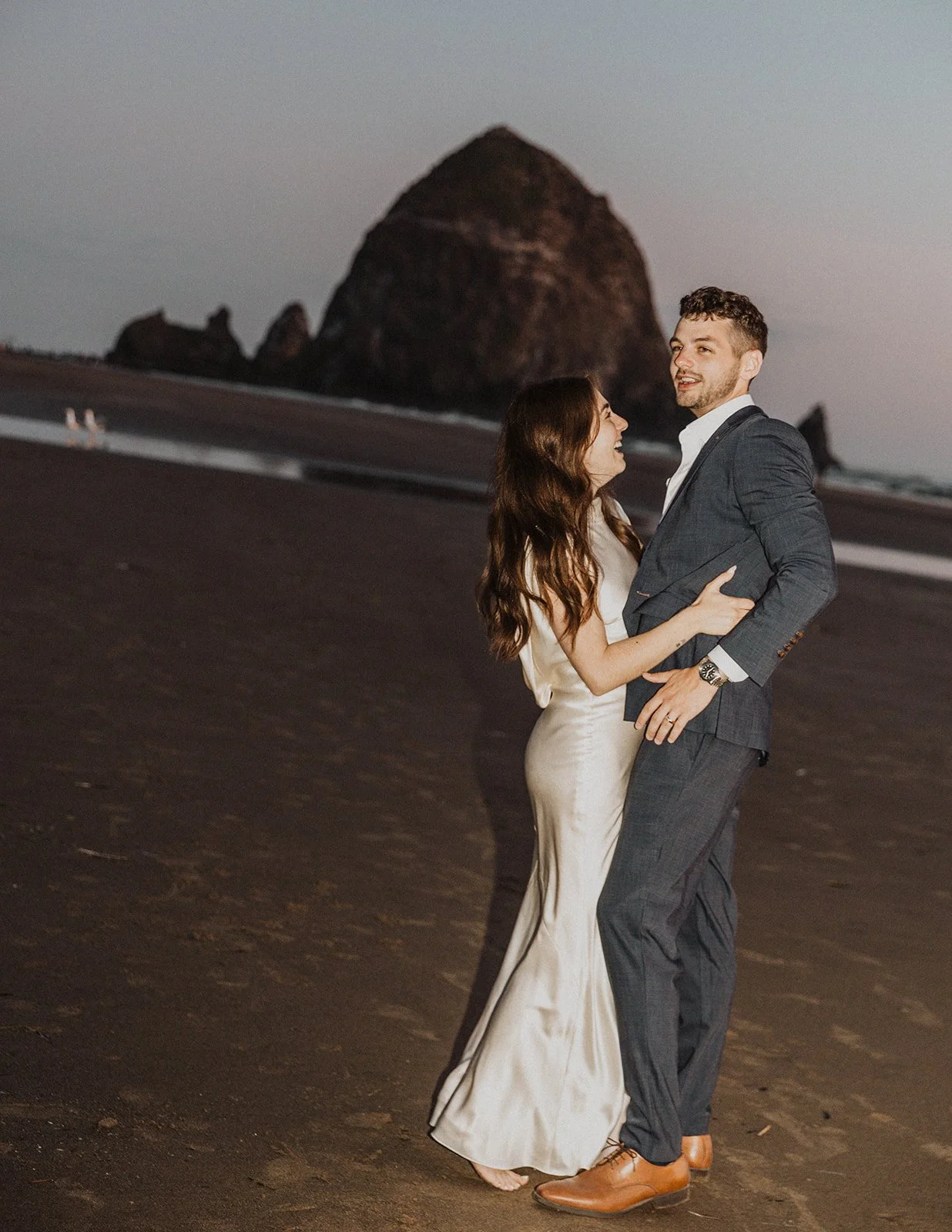 Couple laughing and dancing barefoot on Cannon Beach after their intimate wedding celebration