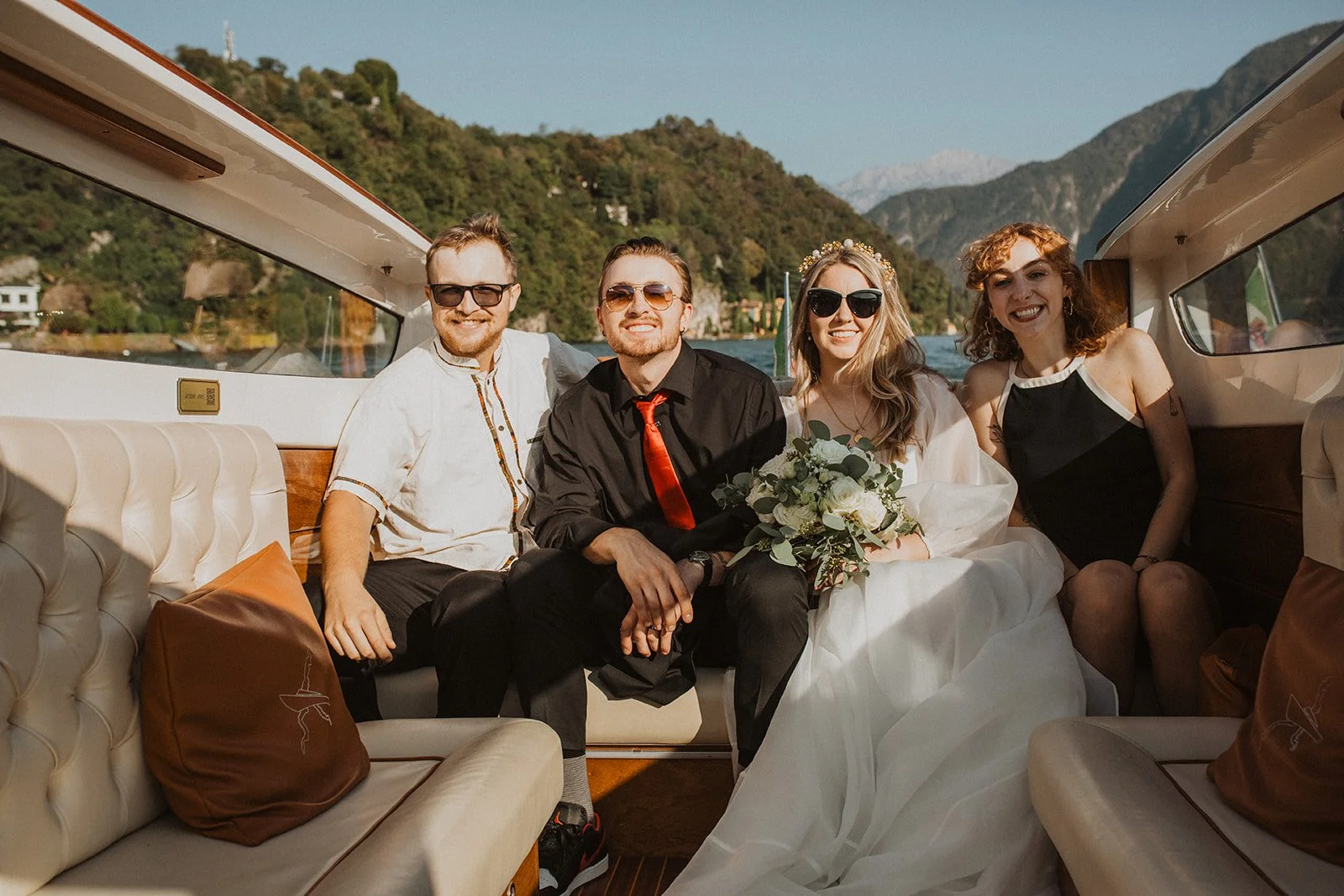 Newlyweds celebrating aboard a classic wooden boat with close friends during a Lake Como elopement.