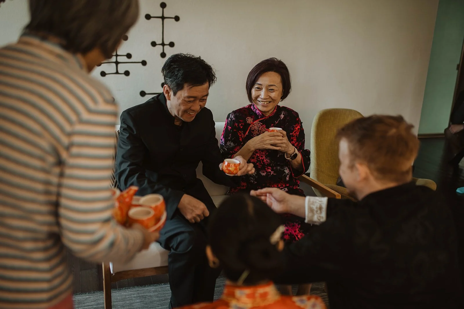 Family members smile and share tea during a traditional Chinese wedding tea ceremony held before the wedding celebration.