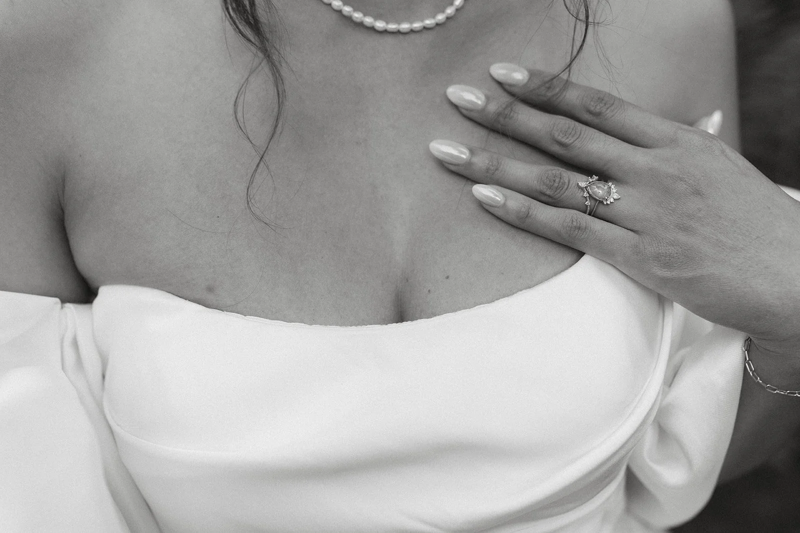 Close-up of the bride's engagement ring, pearl necklace, and off-the-shoulder wedding dress during a Bridal Veil Lakes wedding.
