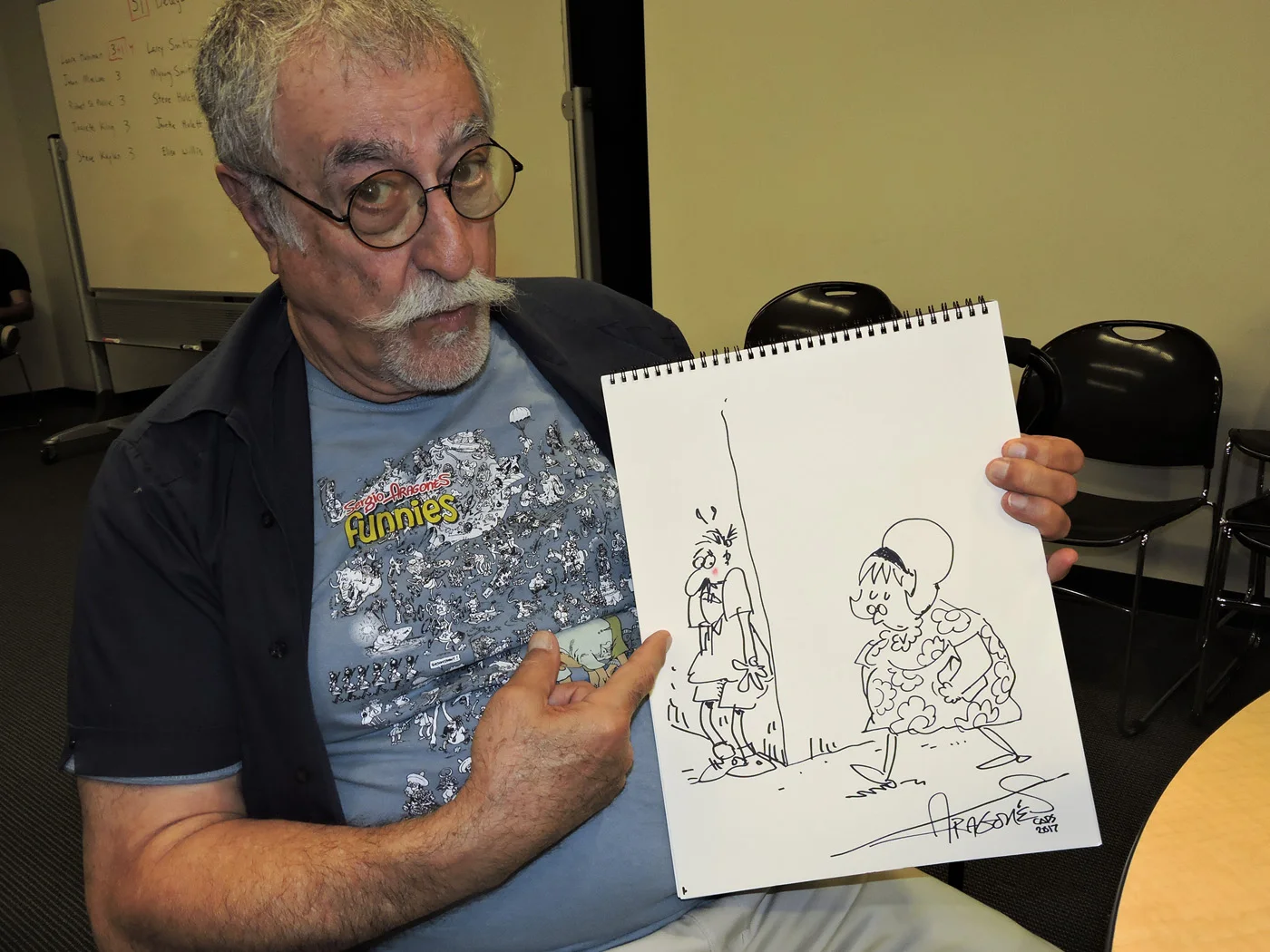 Sergio Aragonés with a 2018 drawing of Fanny Hillman done exclusively for Hogan’s Alley , the first time in years Aragonés had drawn the character. Photo by David Folkman
