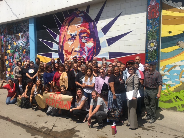 Relatives, friends and supporters of Red Fawn gather in front of a mural of Chief Sitting Bull, whose visions inspired warriors at the Battle of the Greasy Grass 142 years ago today.
