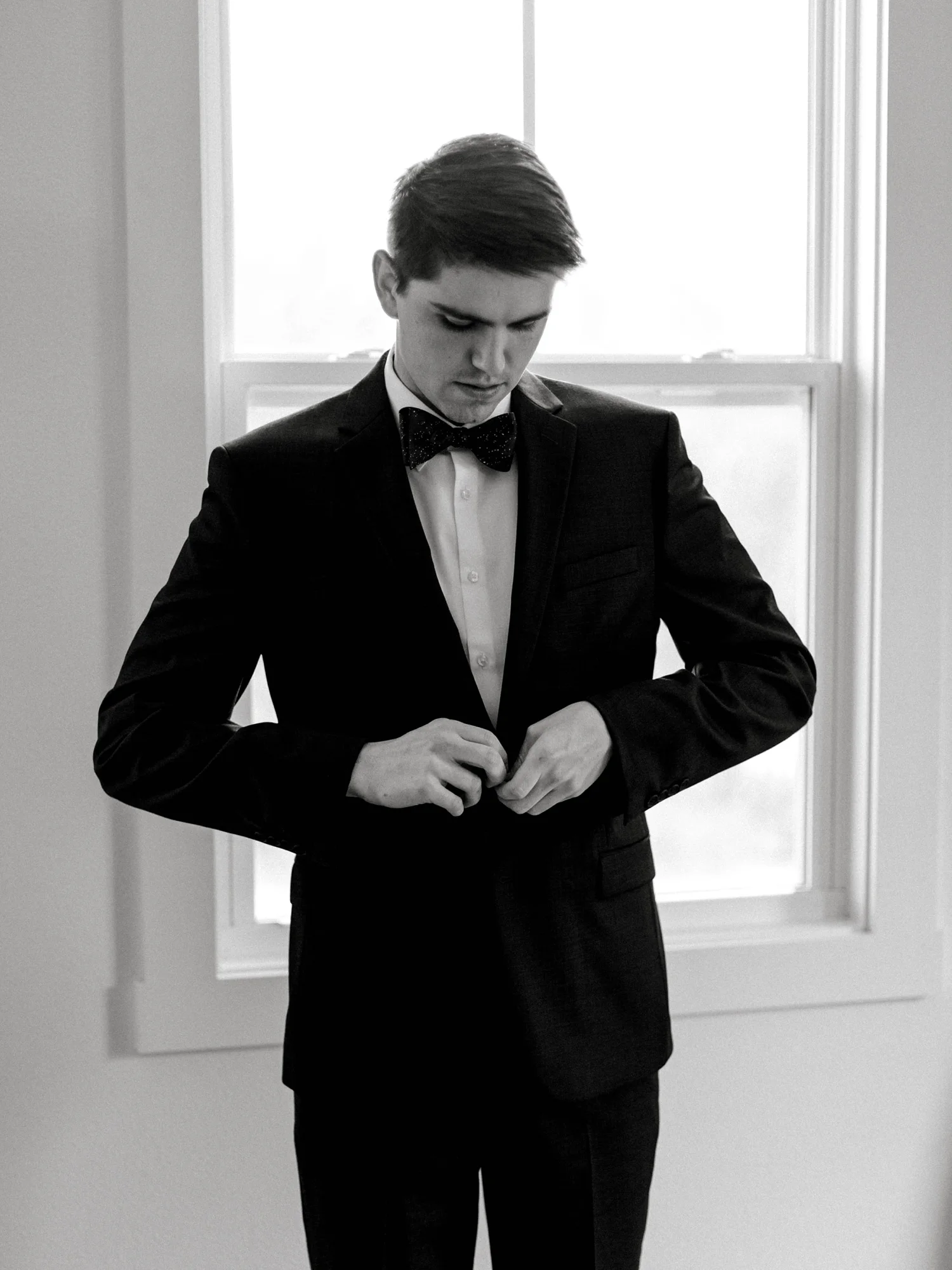 Groom putting on his suit jacket for his wedding.