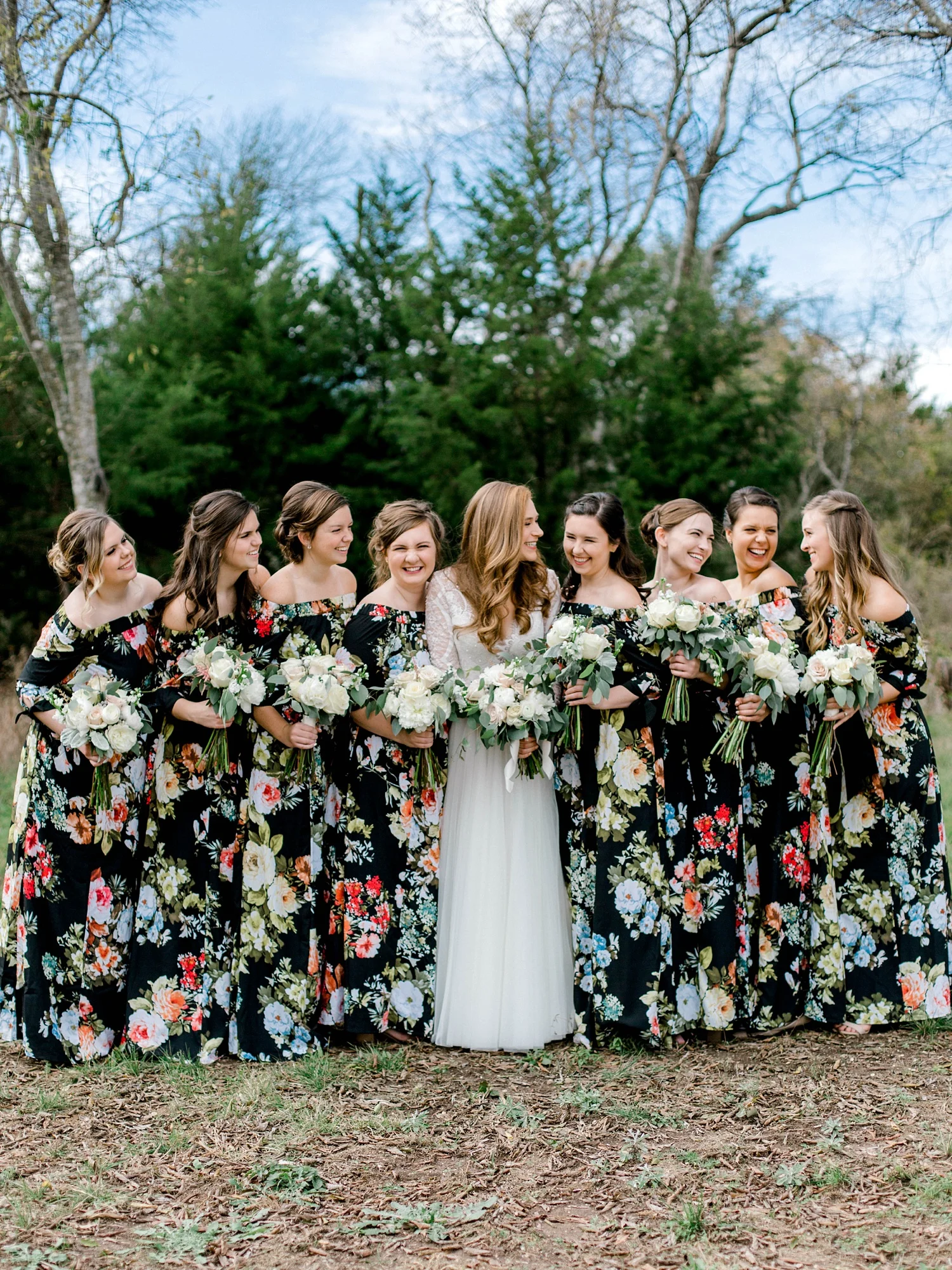 Bride in long sleeve Wtoo wedding dress and bridesmaids in floral off the shoulder bridesmaid dresses.