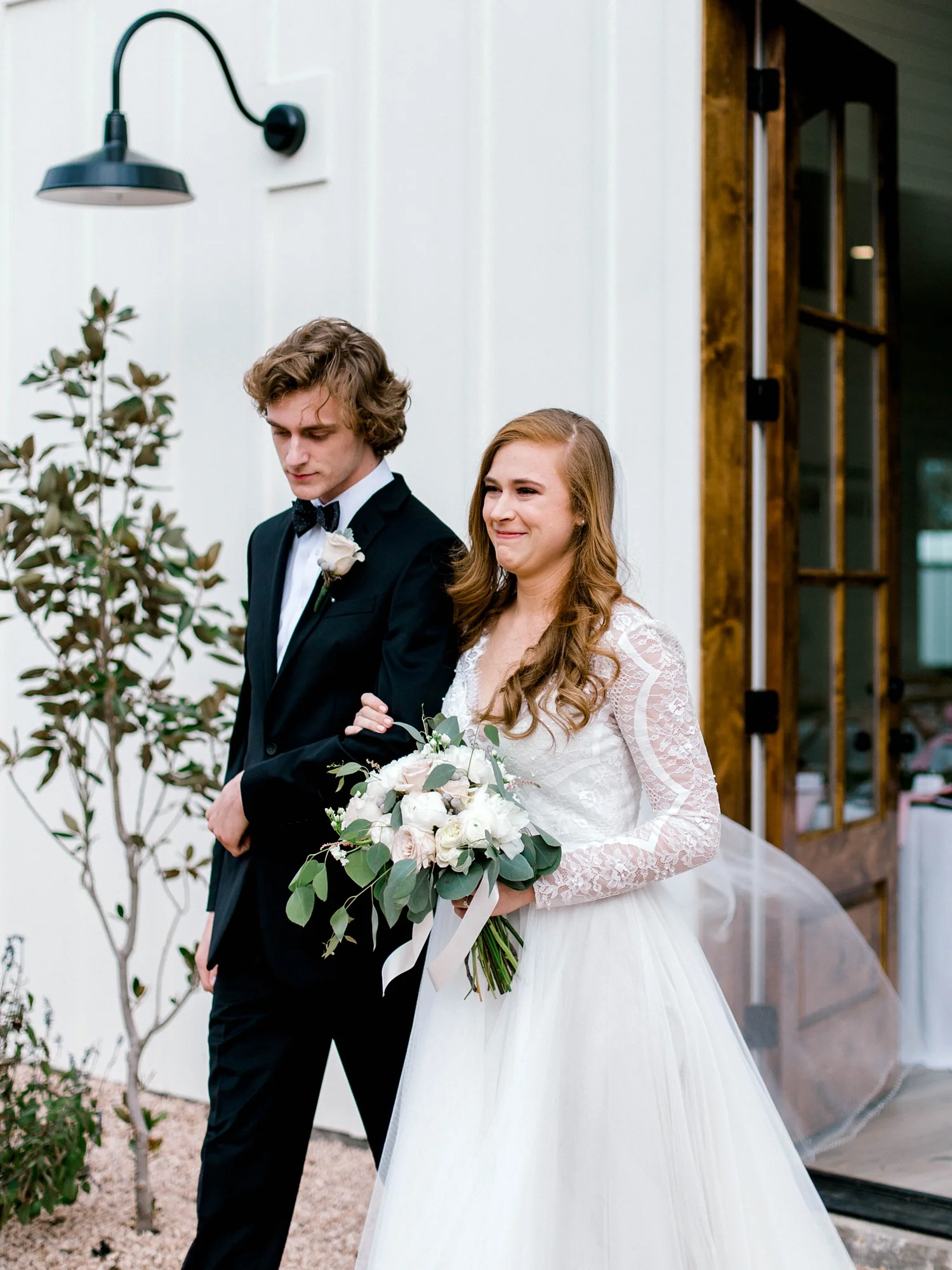 Bride walking down the aisle with her brother in her long sleeve Wtoo wedding dress.
