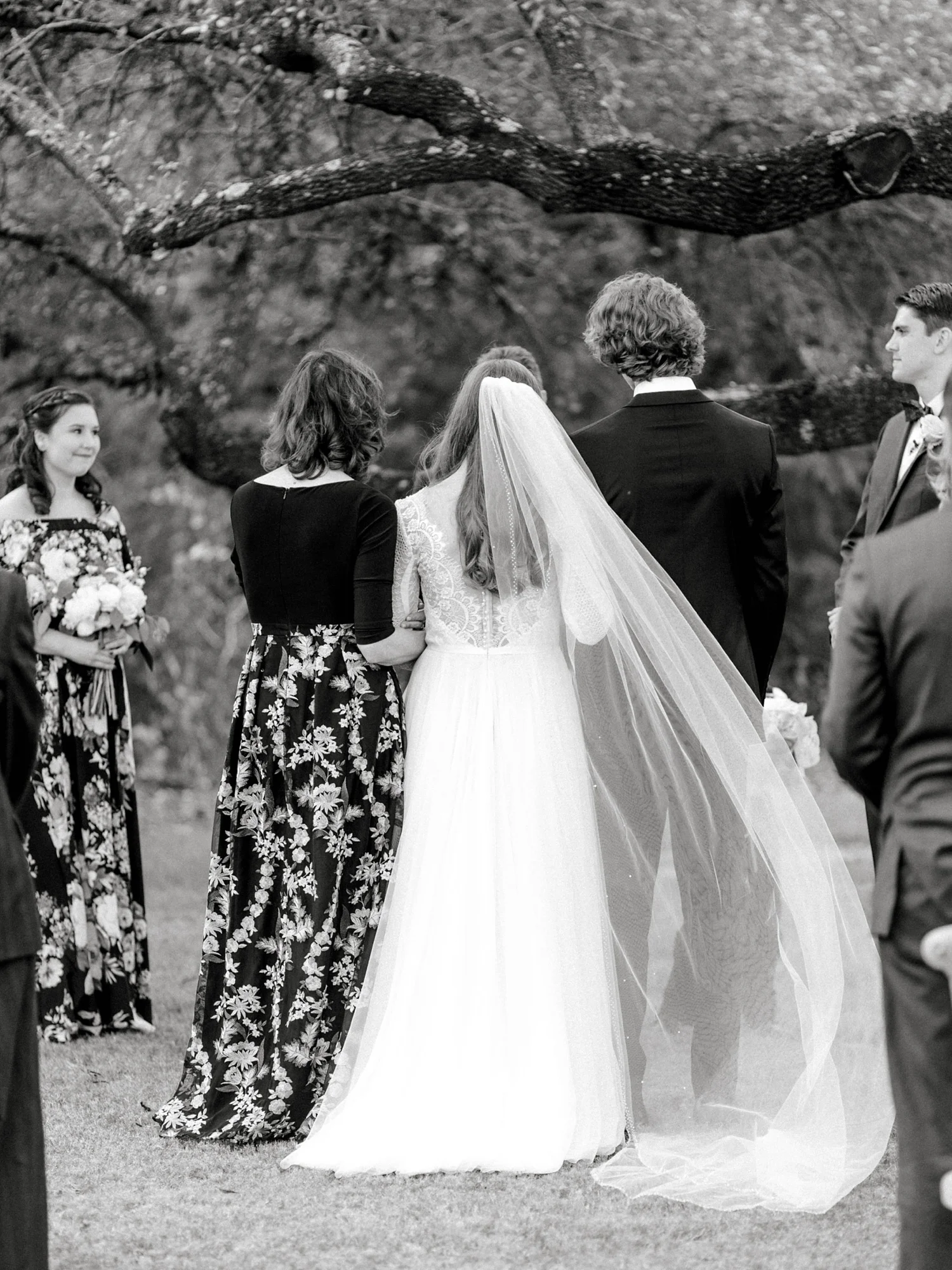 Mother of the bride, bride and brother of the bride standing at the alter with bride’s veil blowing in the wind.