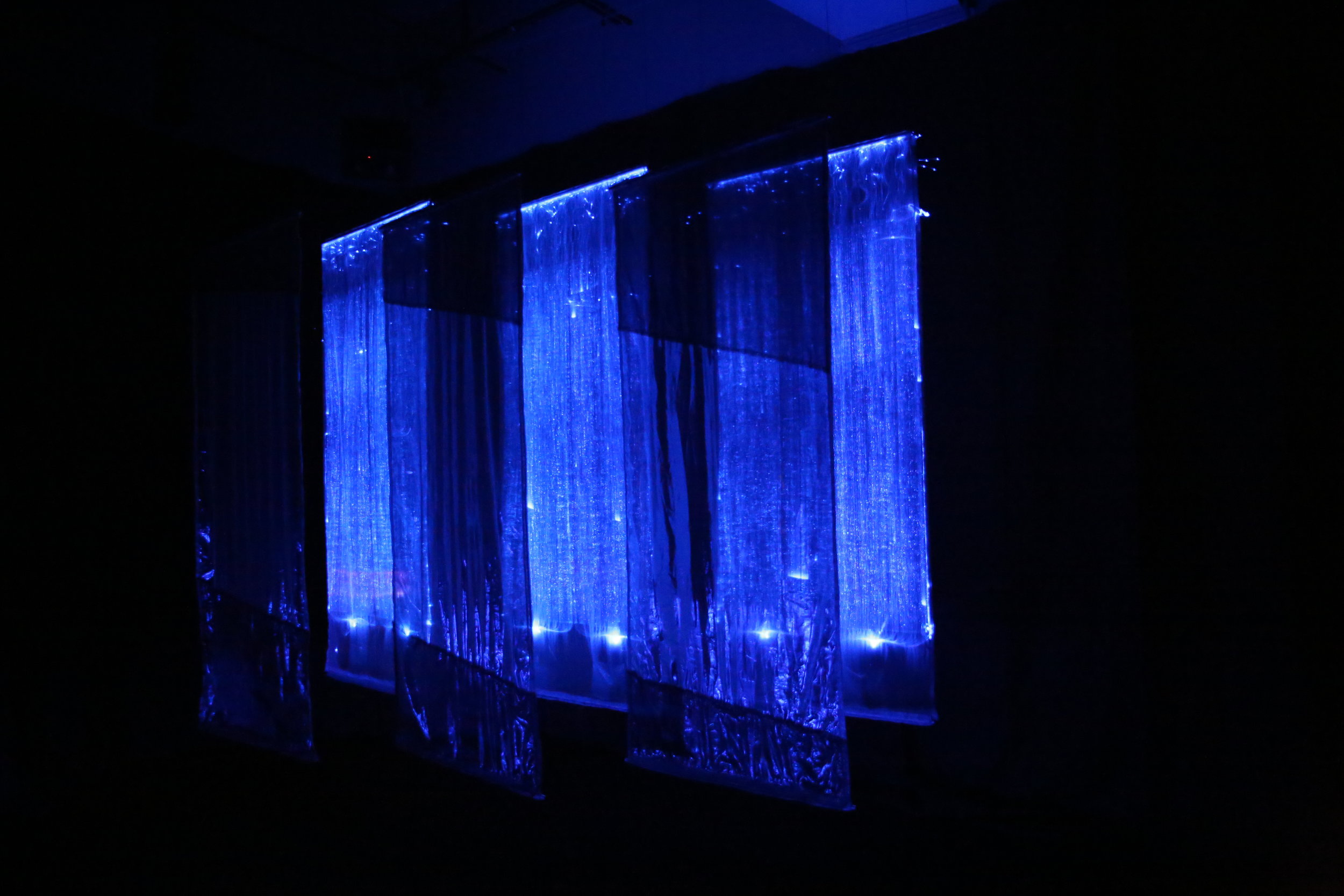   Mikawa , 2017, installation at Jack Straw Cultural Center, Seattle. Six 8’ x 30” hanging panels -- three fiberoptic, and three reflective translucent fabric.&nbsp; Duratrans superimposed photo on light box, 30” x 24” x 6” deep.&nbsp; Shown in fully