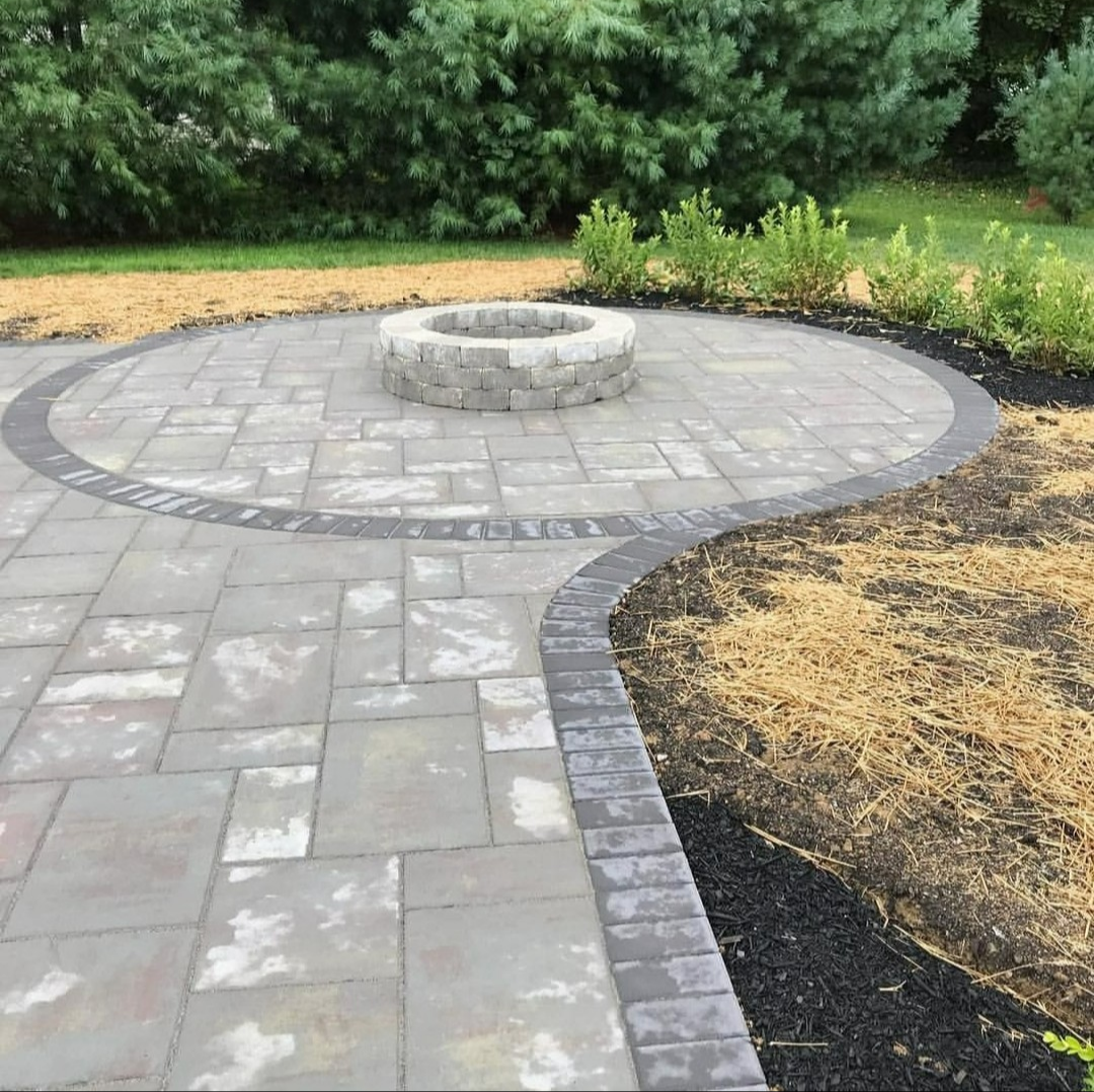 Circular paver patio with built-in fire pit and decorative border, professionally installed as a custom hardscaping feature for outdoor living and backyard entertaining in Northwest Arkansas.