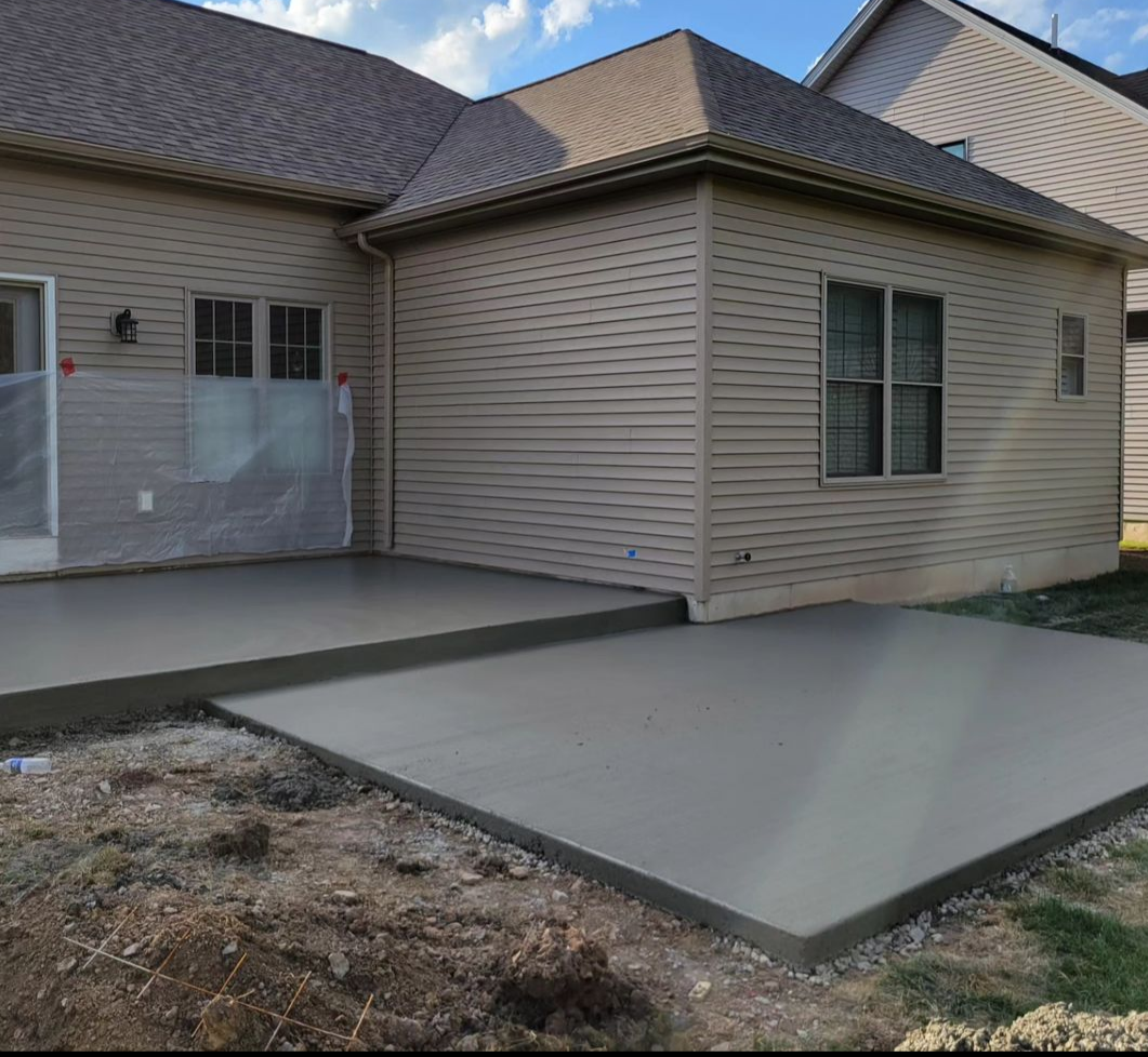 Freshly poured concrete patio slab installed at the back of a residential home, providing a durable hardscape foundation for outdoor living spaces in Northwest Arkansas.