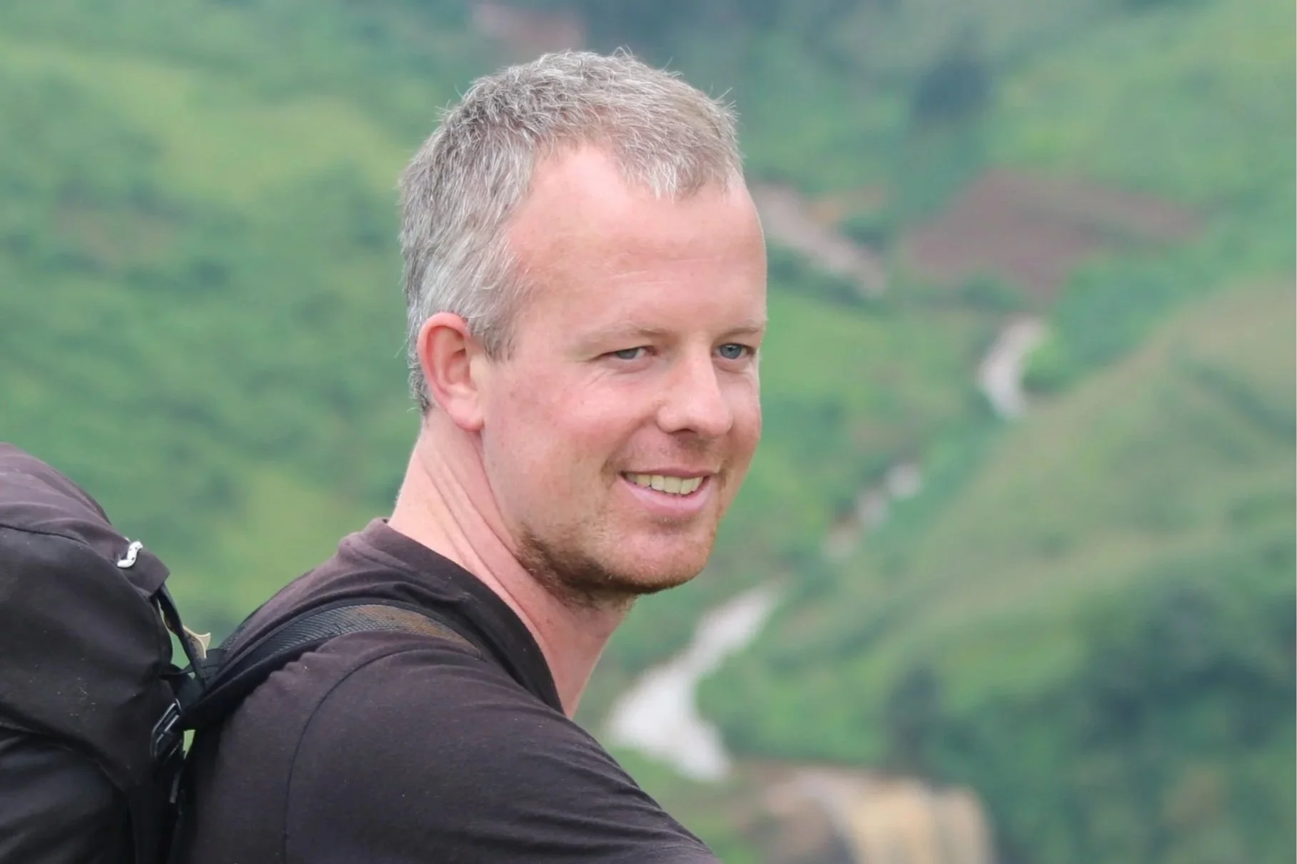 Mount Elgon storyteller Daan during the Mosopisiek Trail experience with a remote waterfall on the background.