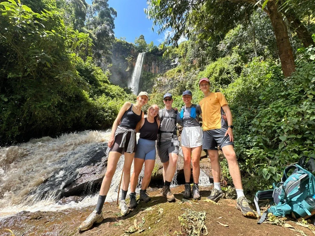 Happy group of hikers in front of Kaptokwoi waterfall along the Kapchorwa-Benet trail. Mount Elgon, Uganda.