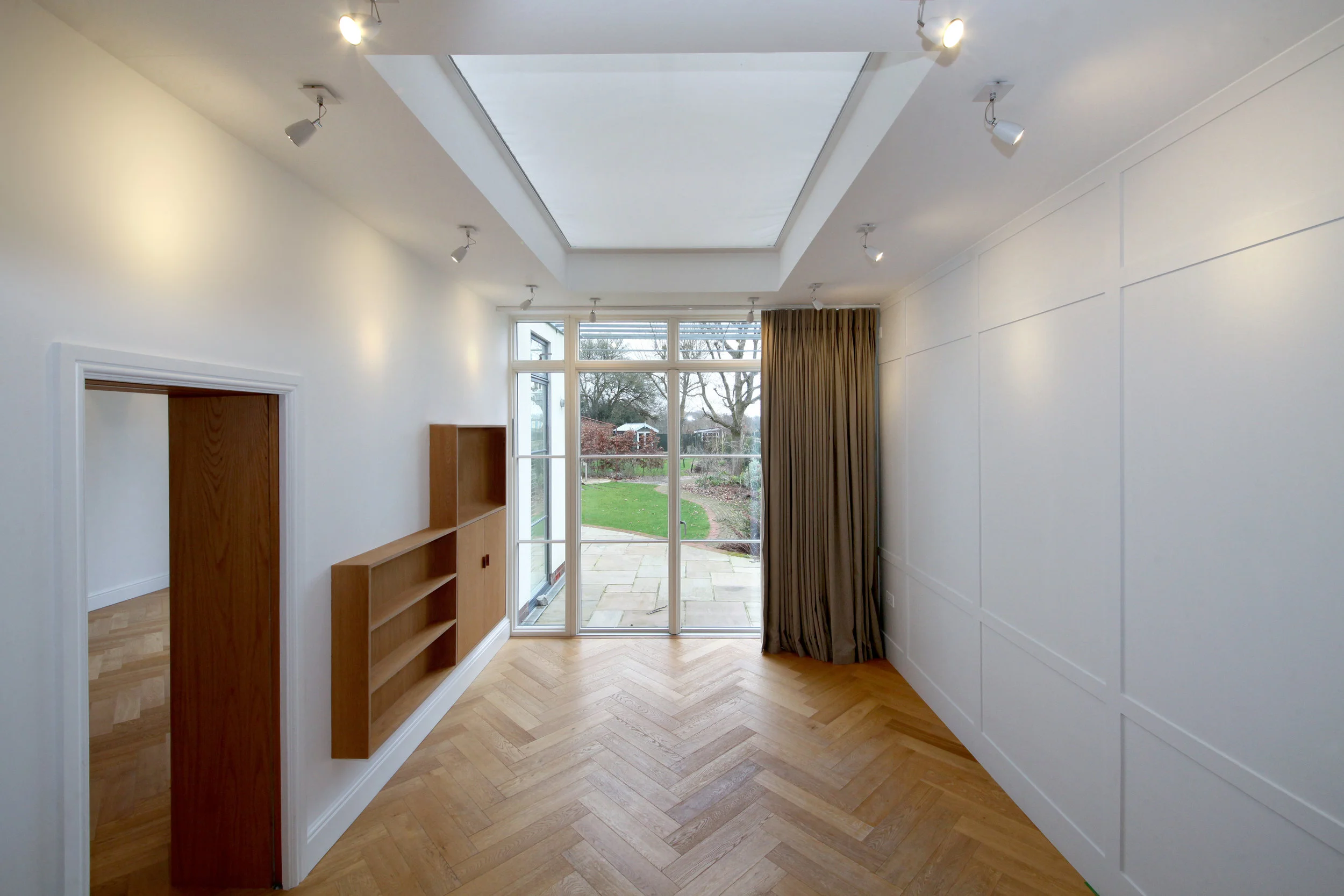  Dining room with Oak veneer plywood AV unit and showing the reverse side of drawing room bookcase with concealed sliding door.  Hand painted wall panelling on right. 