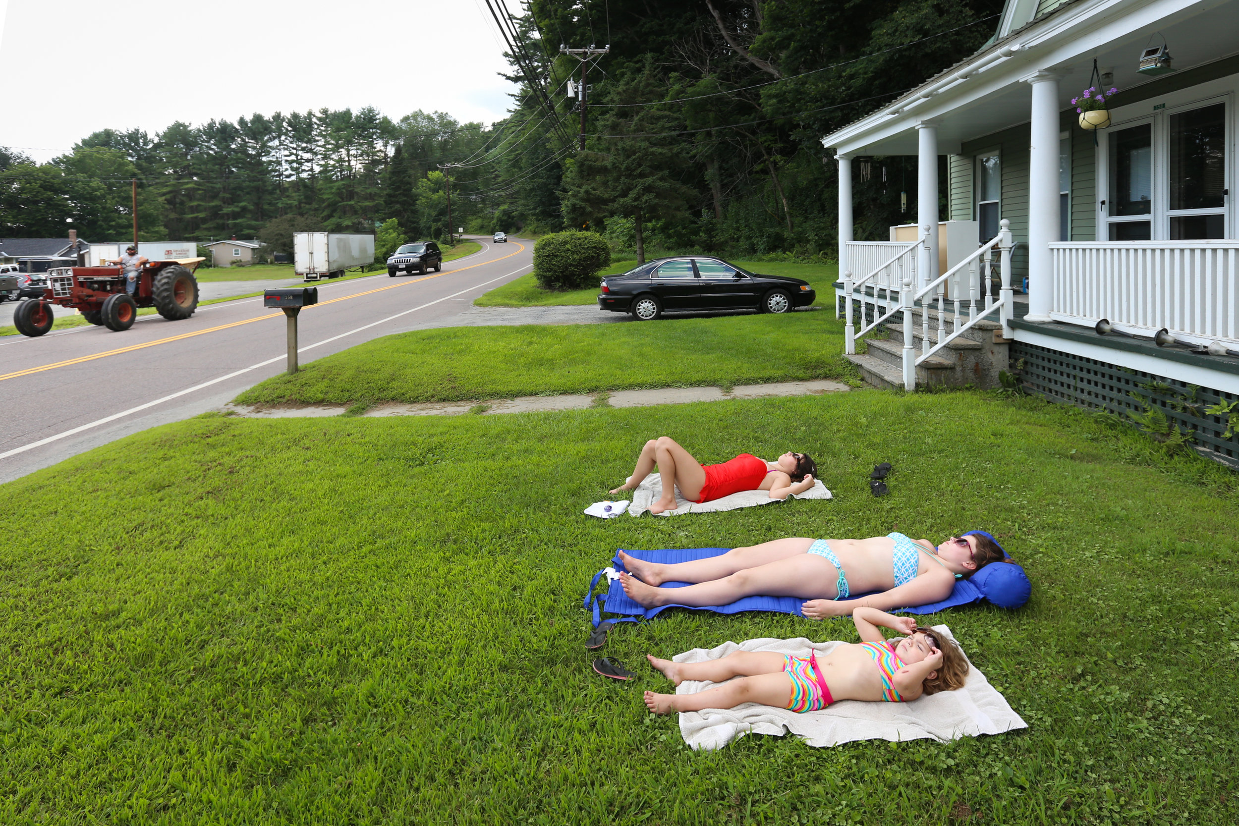  Madison Garrow, Lylah Reynolds, and Sadie Garrow,&nbsp;sunbathe on the front lawn of Reynolds' home in Windsor, Vermont 