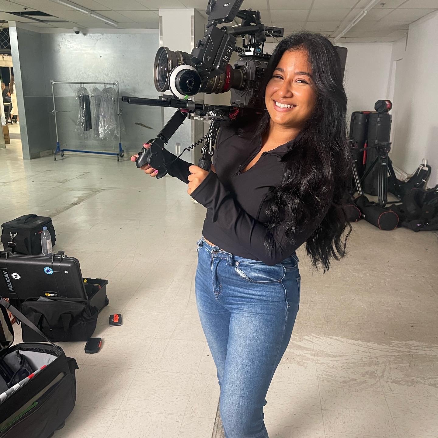 Smiling videographer holding a professional cinema camera rig in a production studio