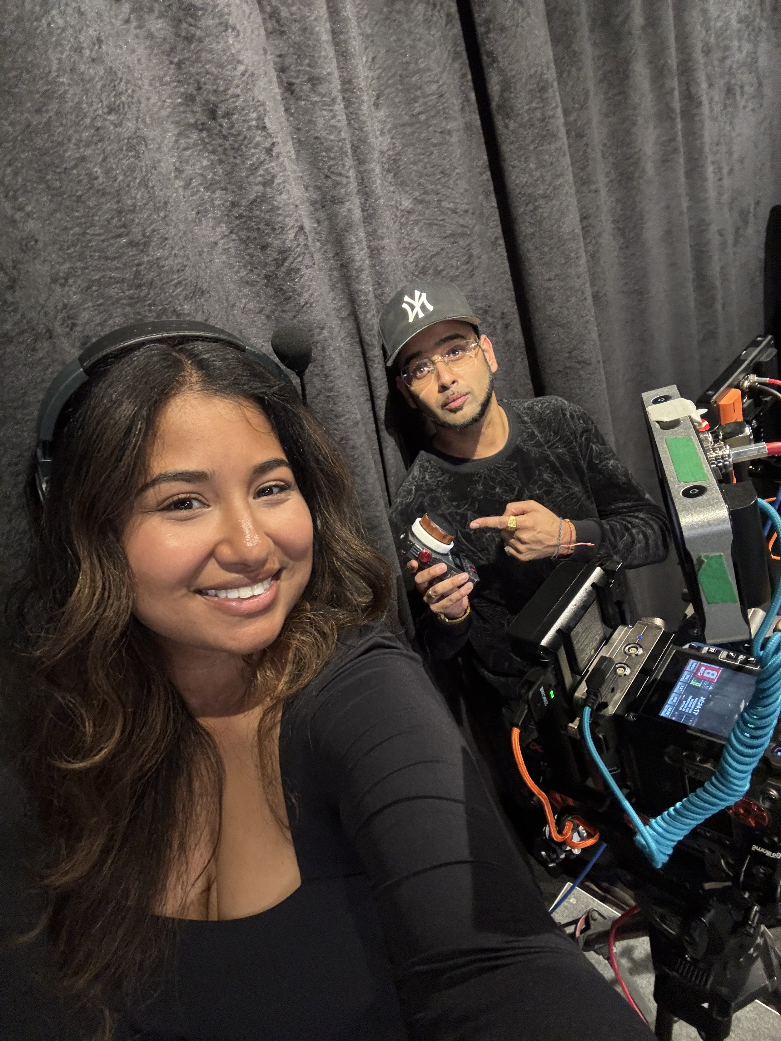 Two people take a selfie inside a film production vehicle surrounded by camera equipment.