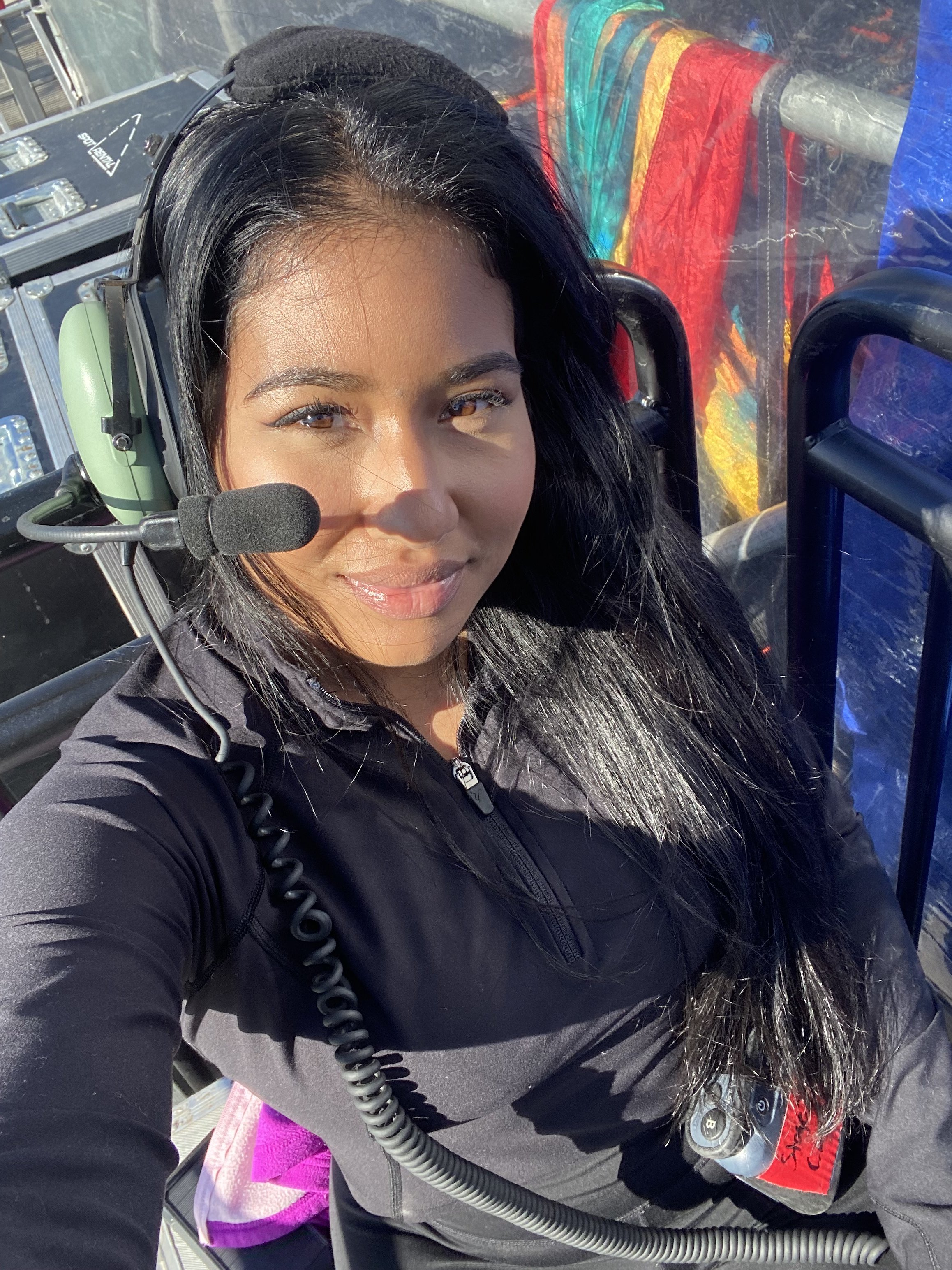 Close-up portrait of a woman wearing a headset and black jacket inside a colorful amusement ride or vehicle