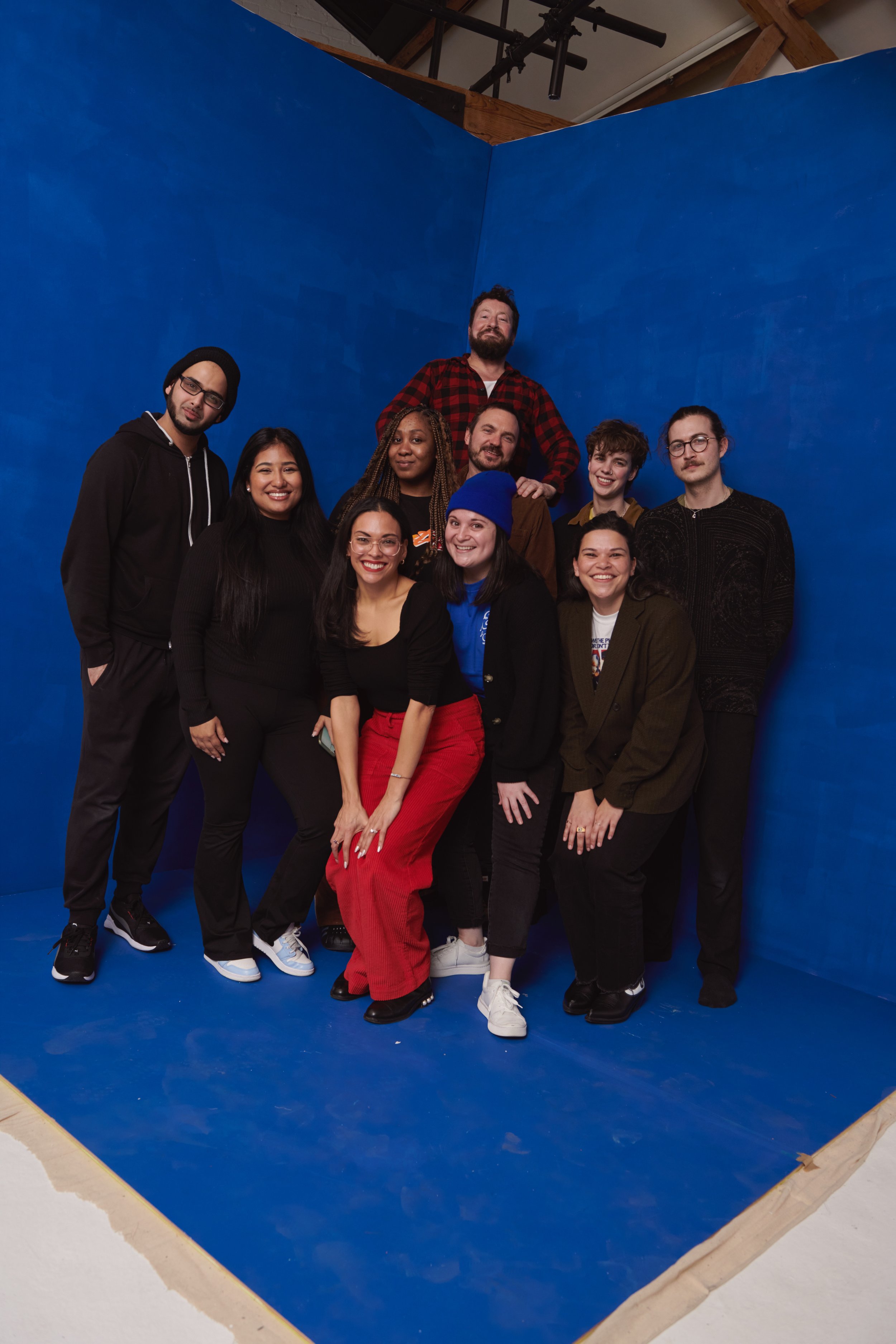 Group portrait of diverse adults posing together in front of a bright blue backdrop.