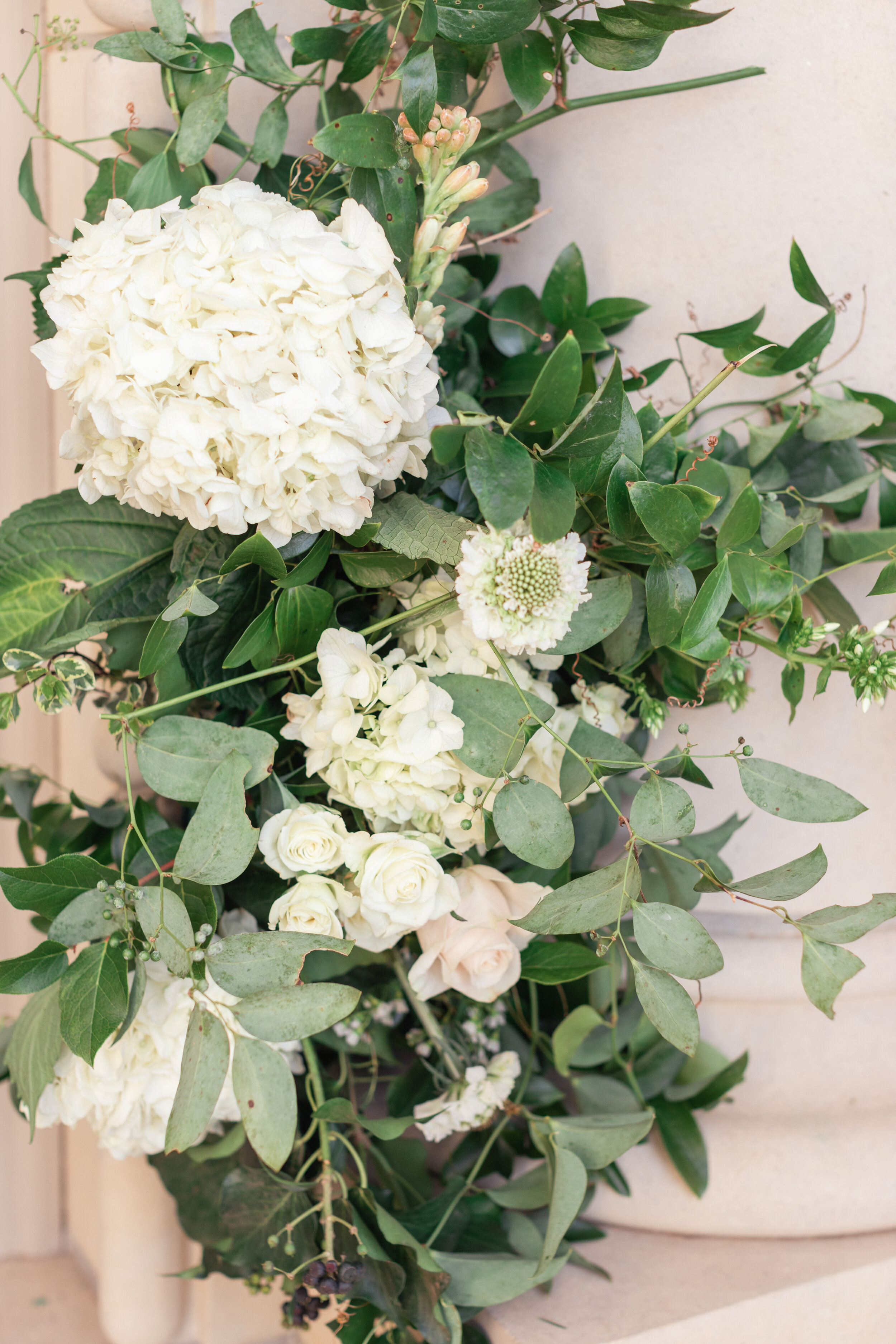White hydrangea floral wedding arrangement with green leaves and white spray roses