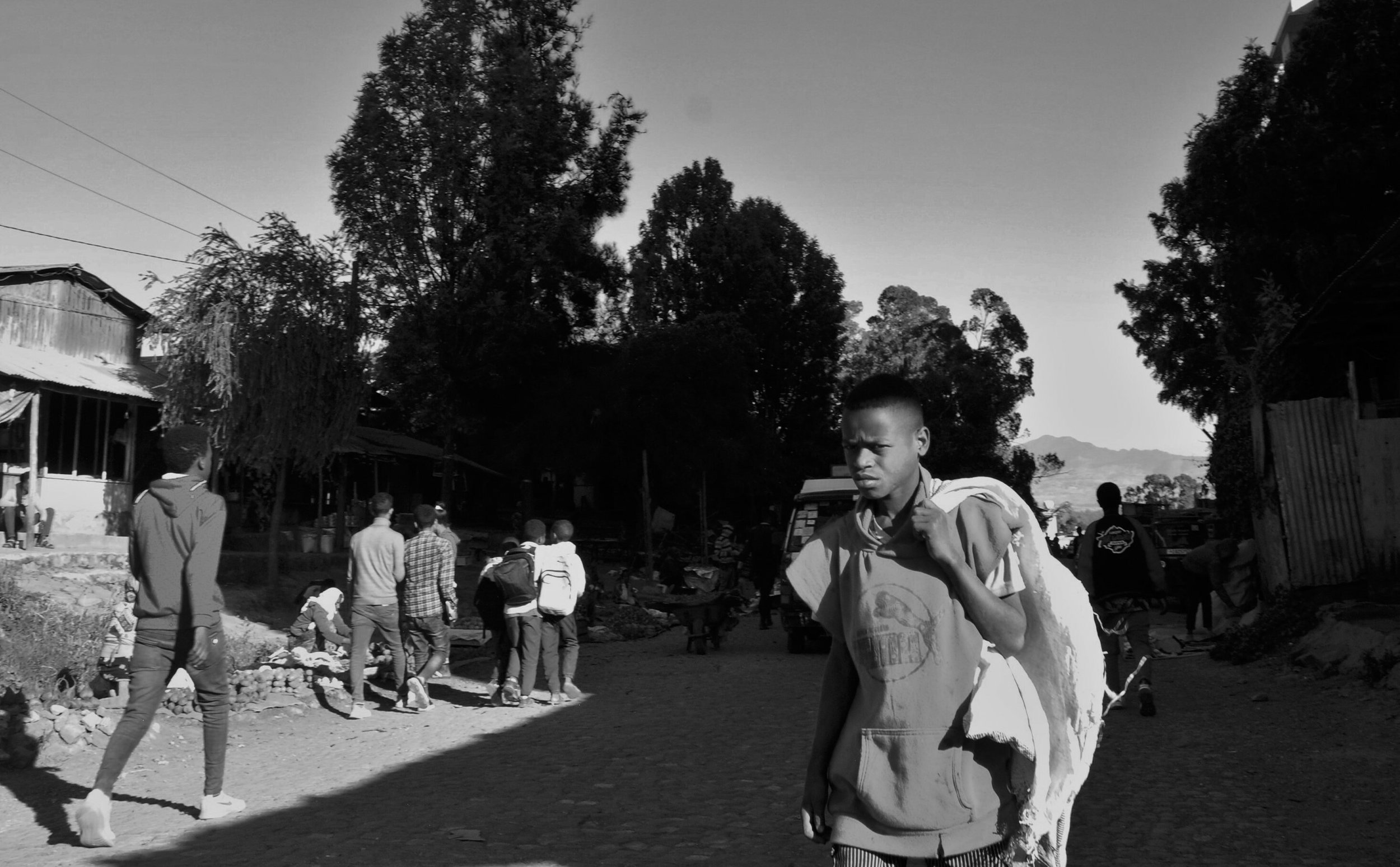  13. In the photo, a young boy is seen carrying multiple plastic bags in his hands. He appears to be working. He has a determined look on his face, suggesting he is focused on completing his task. The plastic bags likely contain various items, and th