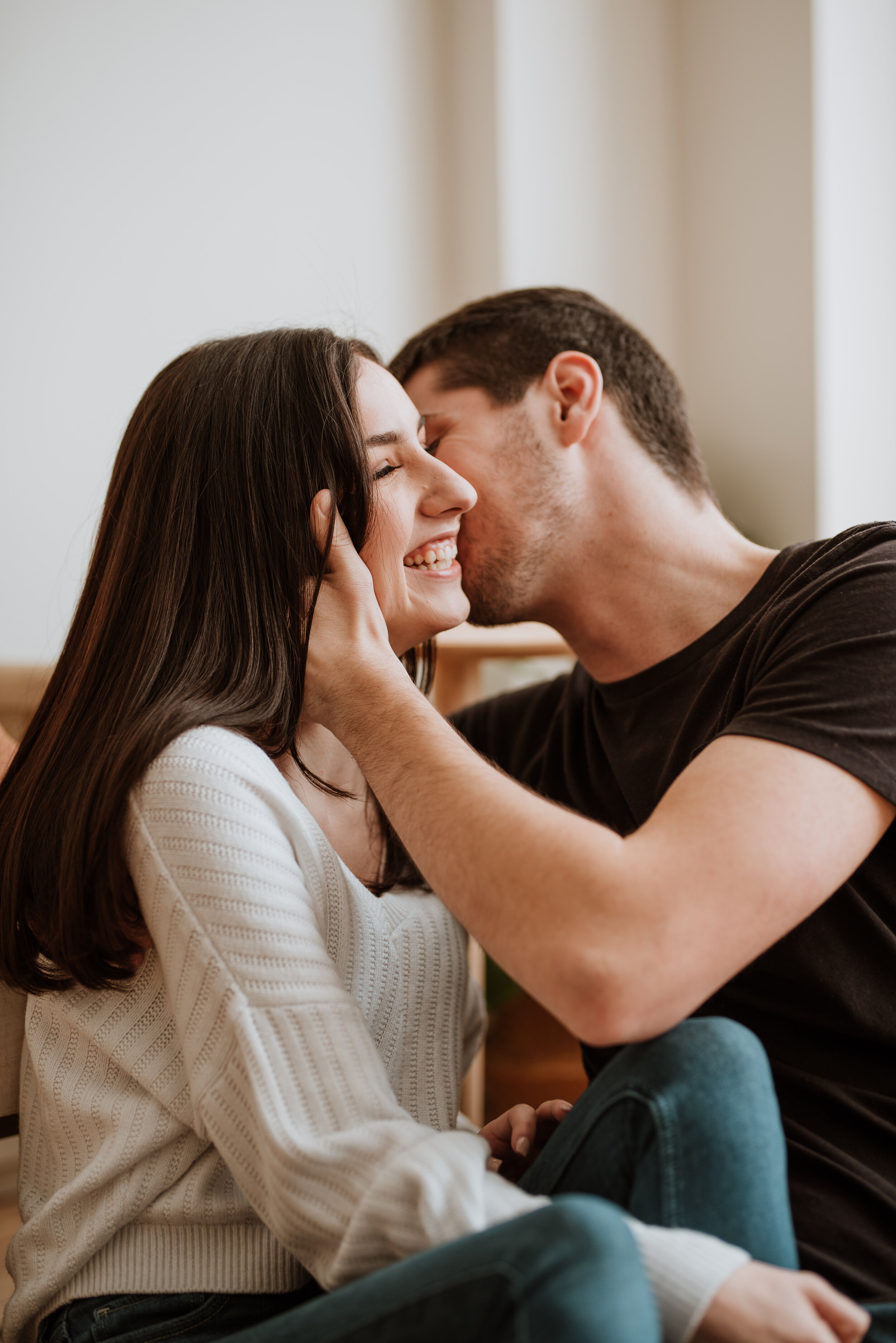 Man kissing woman's cheek while she laughs.
