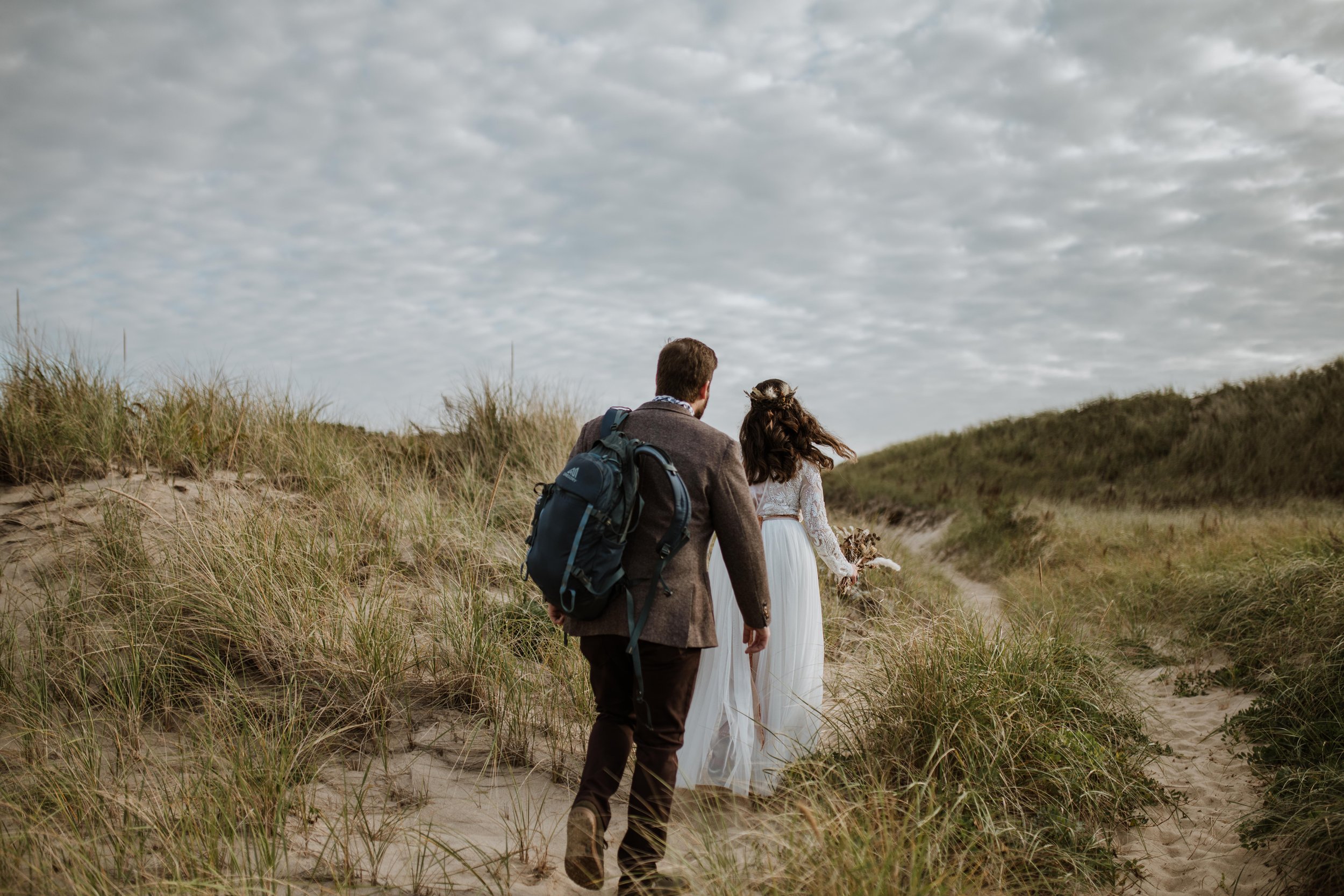 Couple walking out across the dunes along a path. 