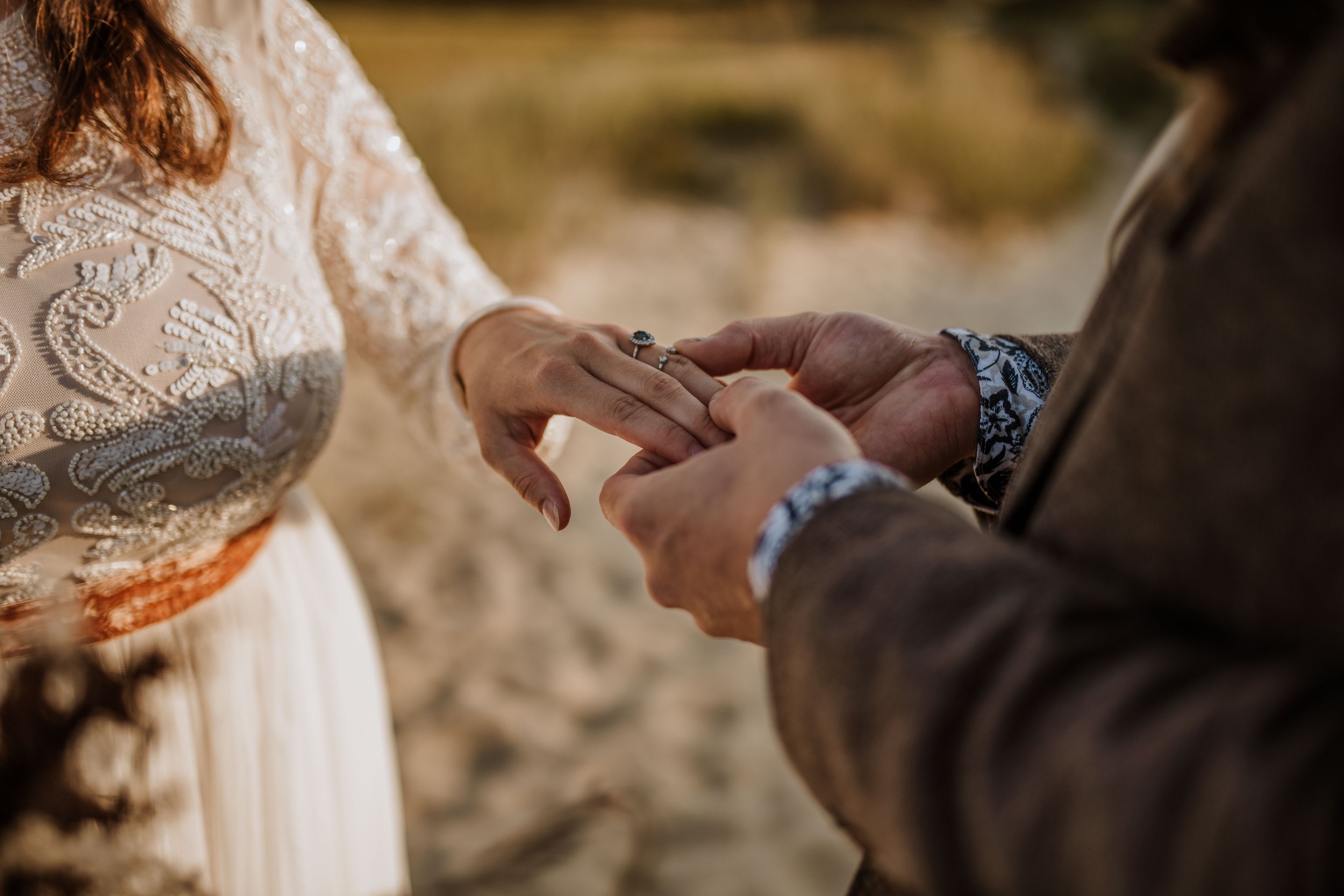 Groom placing ring on bride's left ring finger.