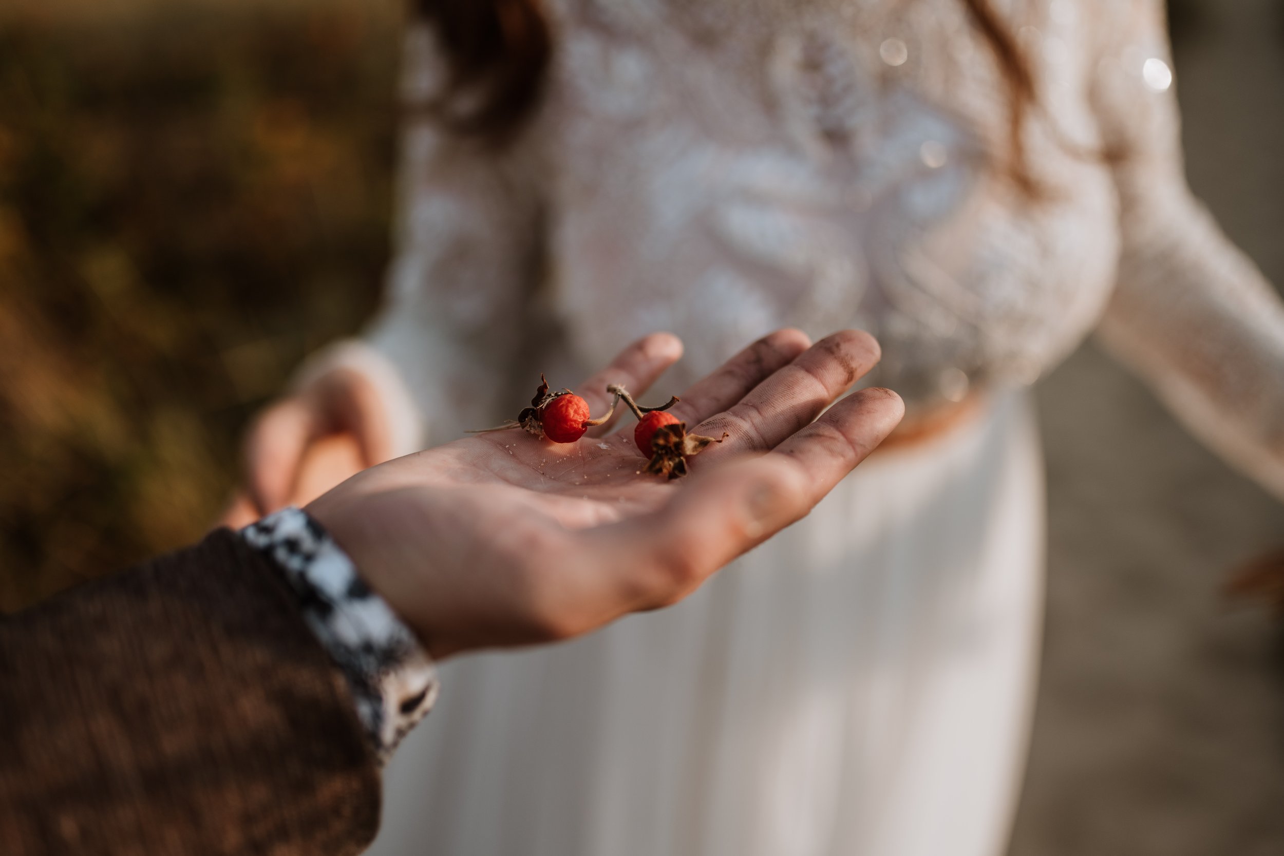 Groom holding rosehips he found along the trail to show his wife.