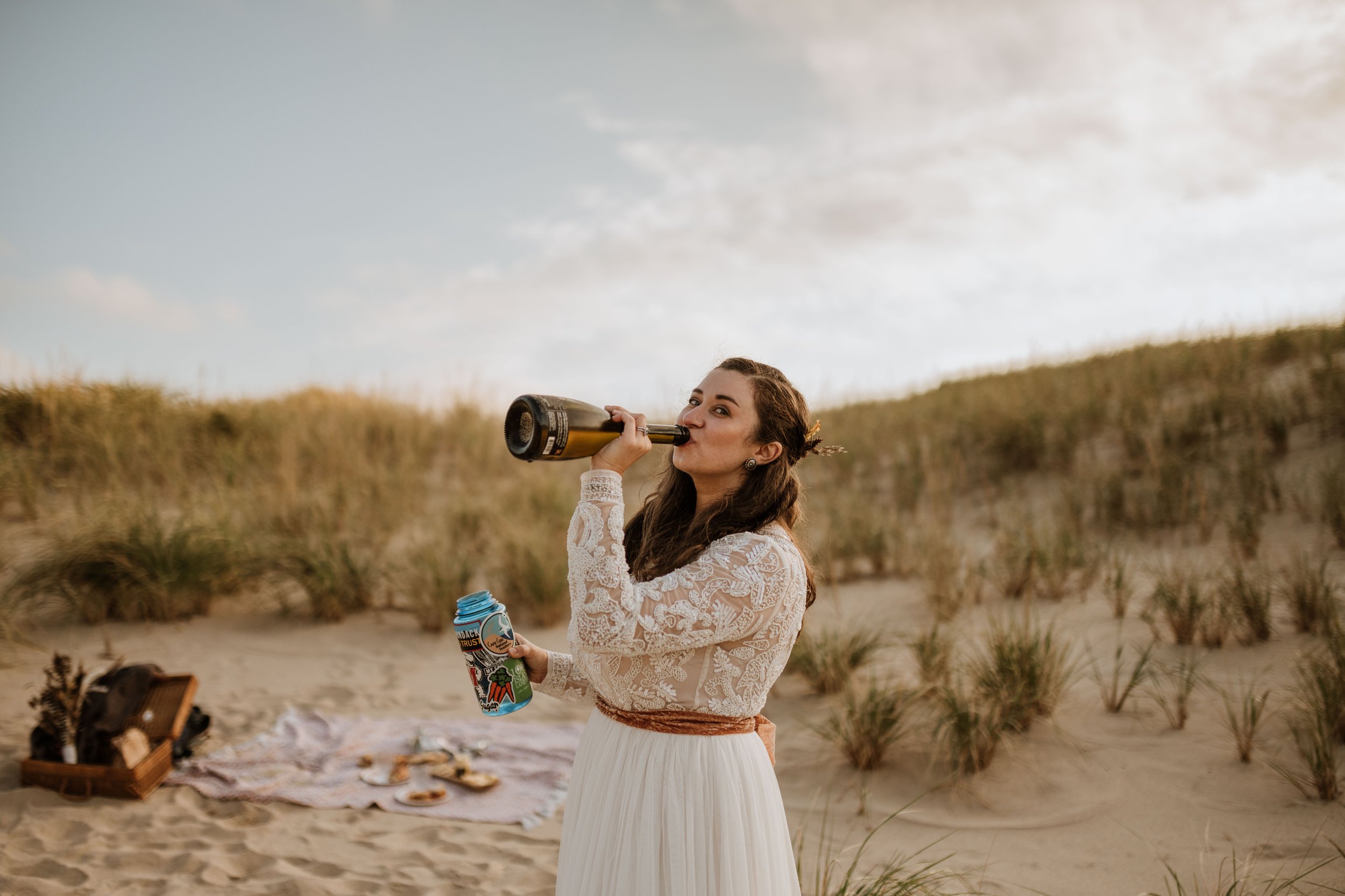 Bride drinking champagne directly from the bottle.