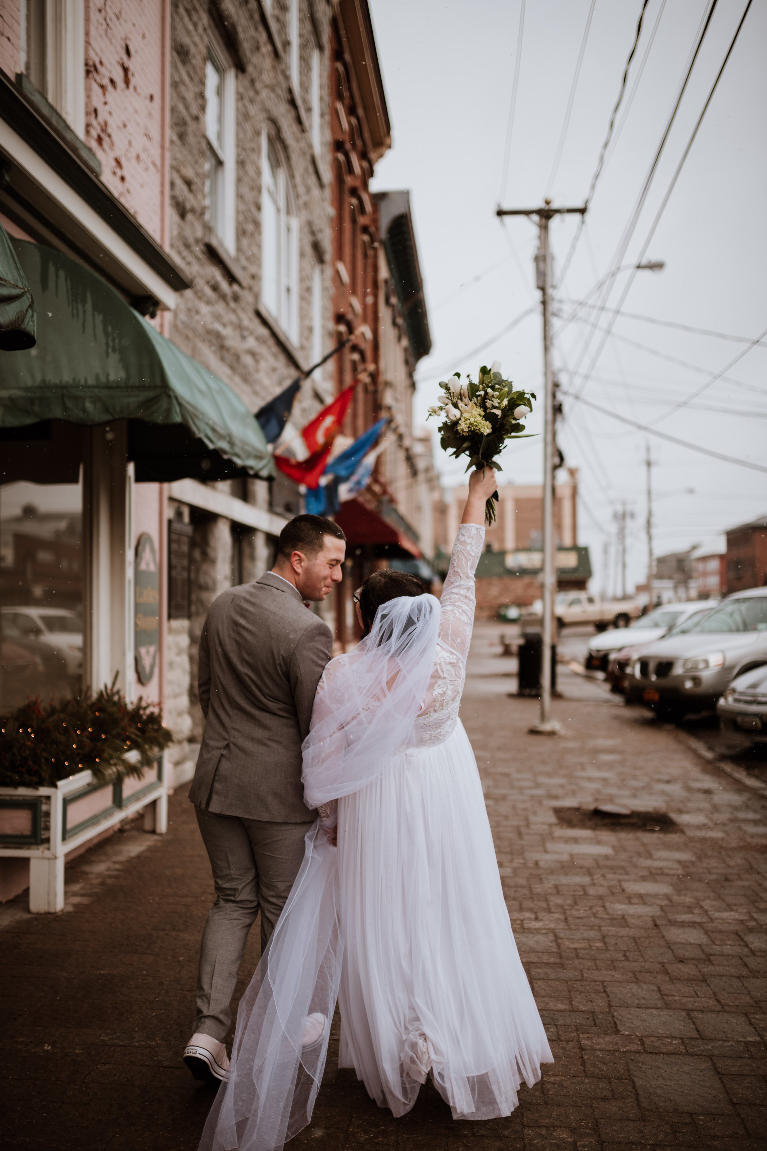 Newlywed couple walking together in downtown Clayton, New York during a light snowfall.