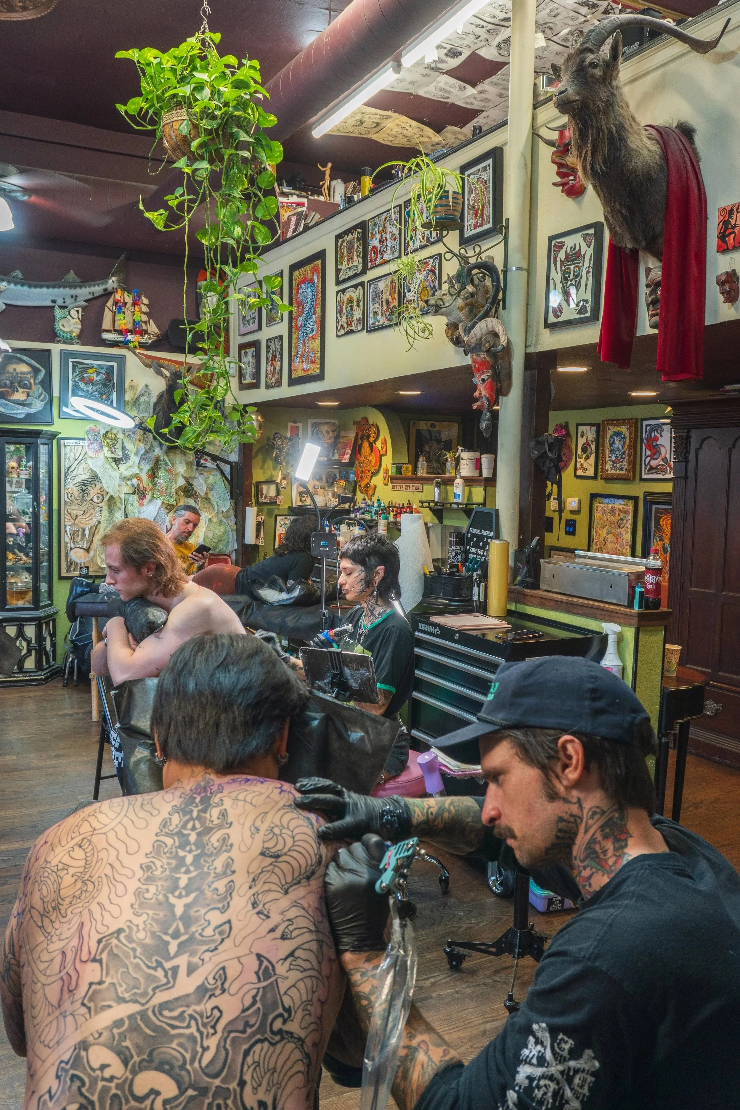 Tattoo artists Keagan Cotie and Ethereal Bloodlet working on back pieces for clients at Landmark Tattoo